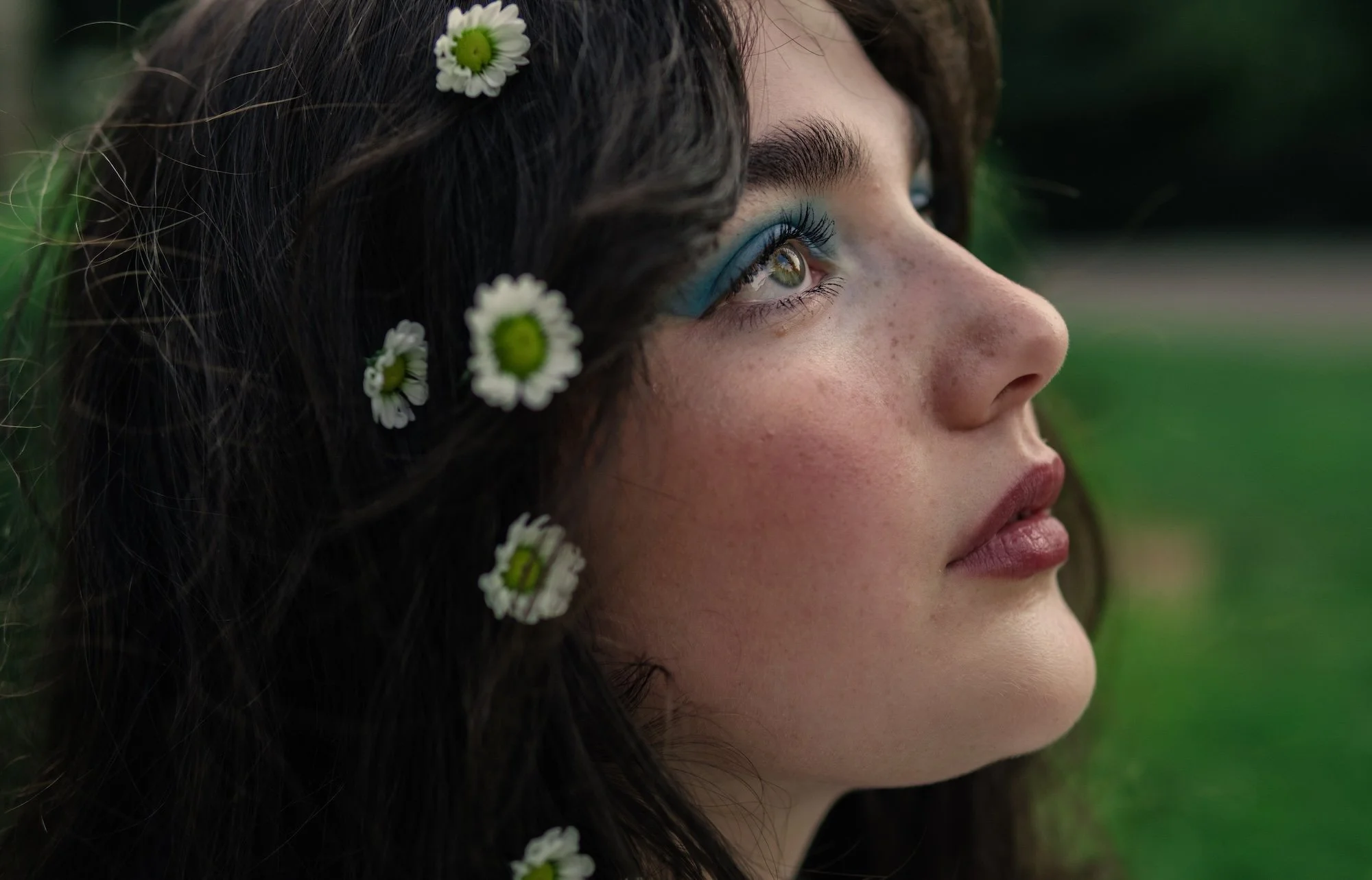 Close-up portrait of woman with flowers in her hair looking upward in soft light