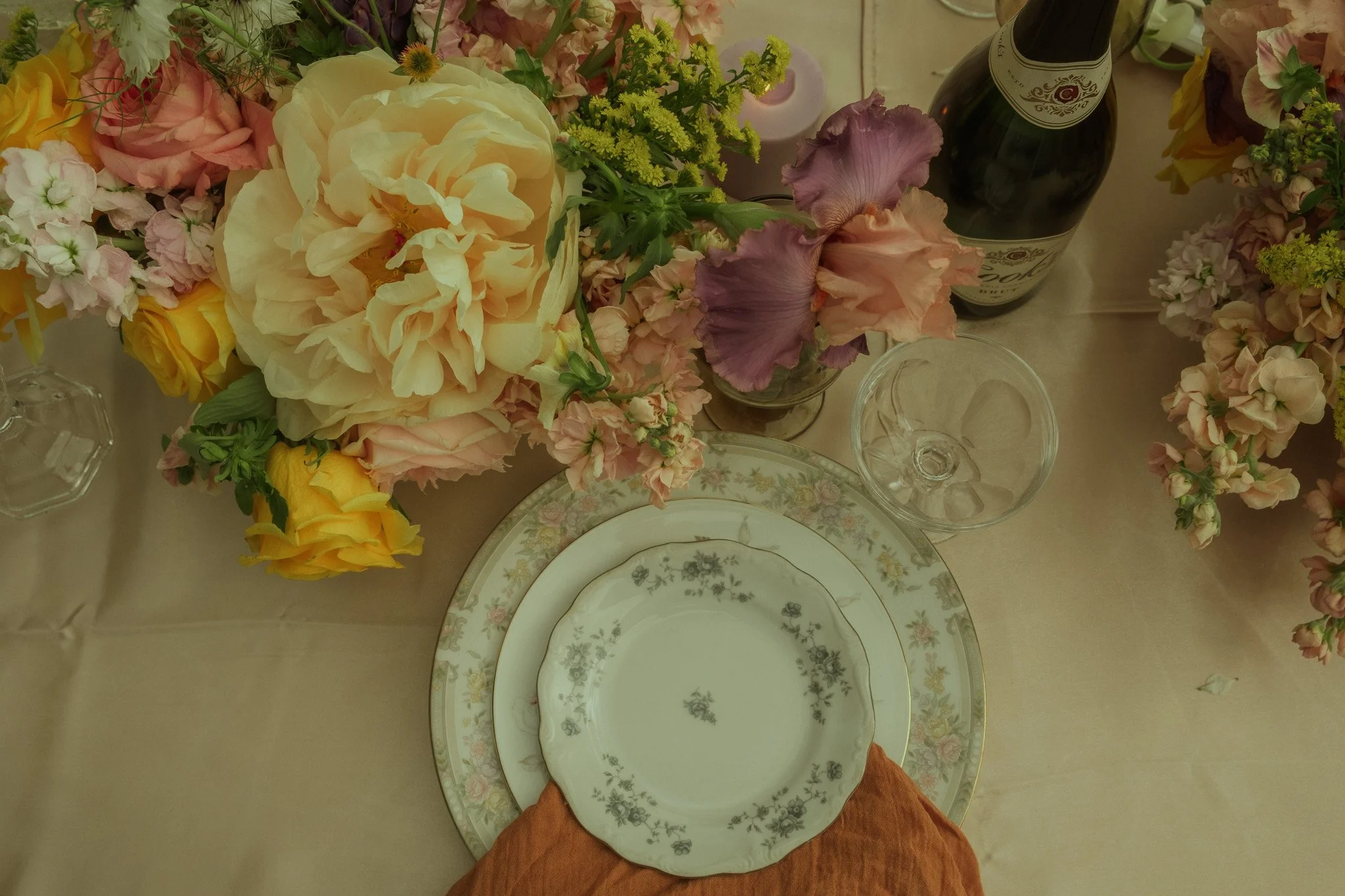 Floral arrangement with vintage plate and glassware in soft, romantic styling