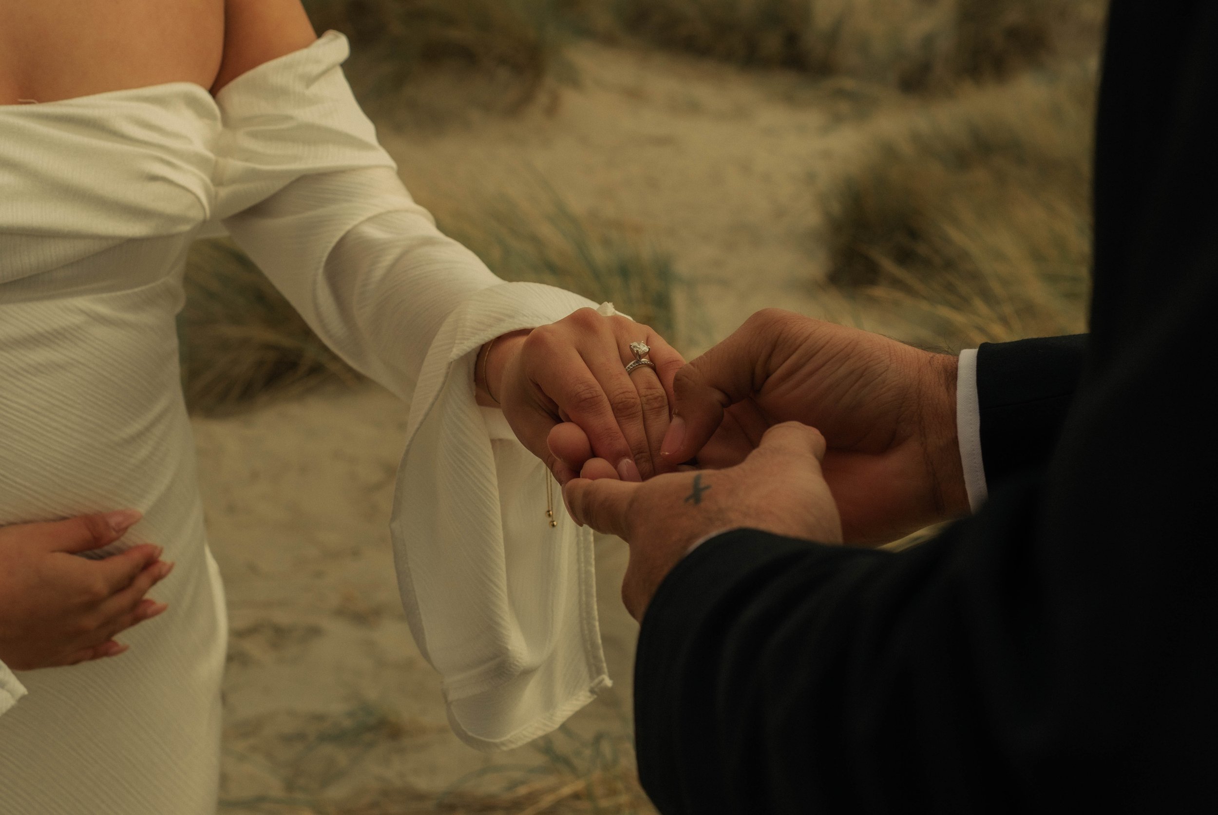 Close-up of couple exchanging rings during outdoor ceremony