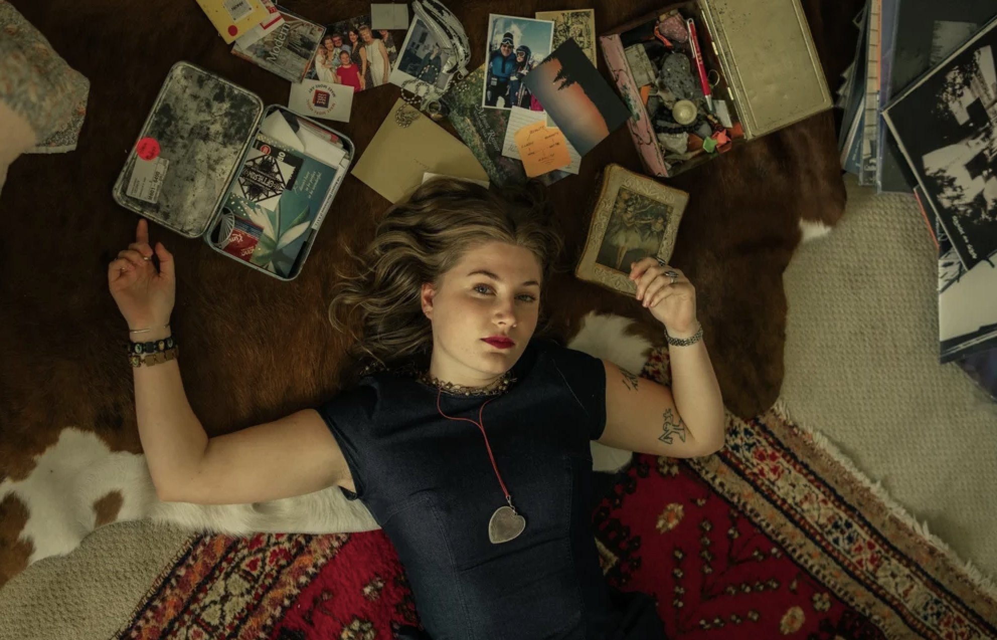 Creative portrait of woman resting among scattered photos and personal mementos