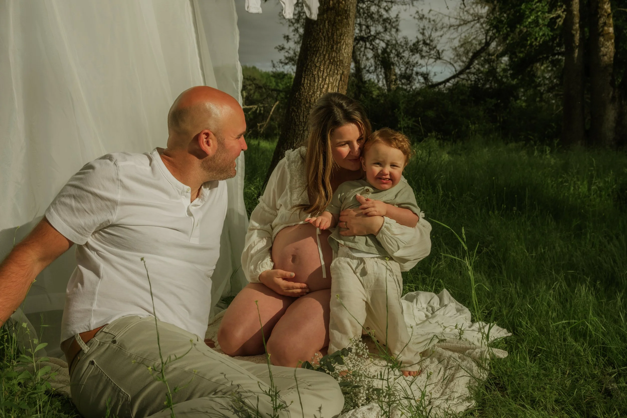 Family sitting together on blanket outdoors, candid moment with young child