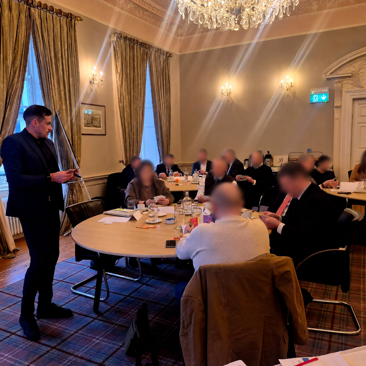 Kieran Lillis facilitating a corporate workshop, with participant faces blurred for privacy.