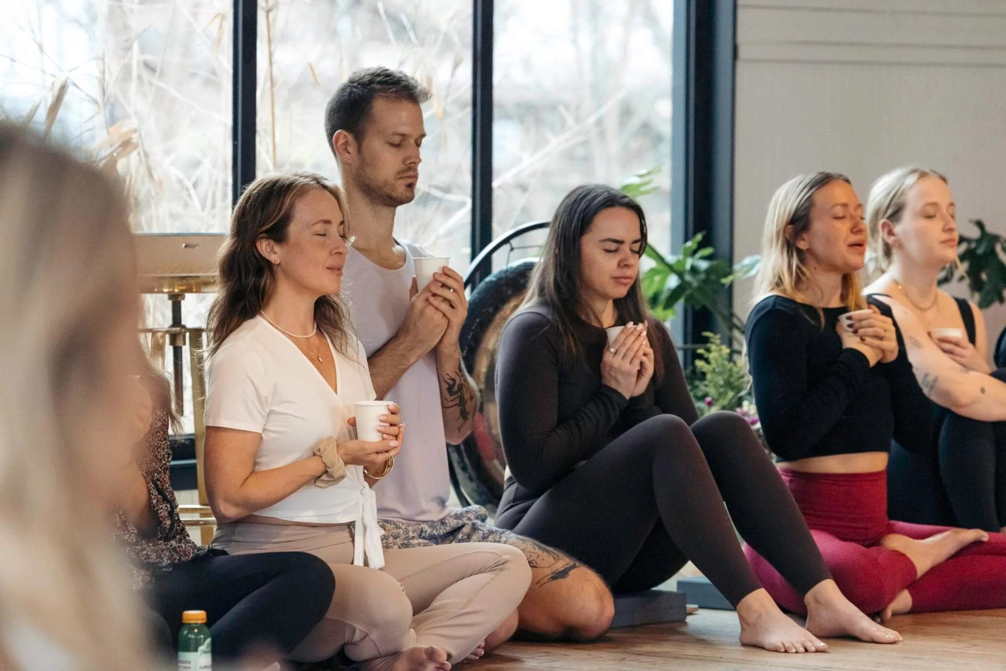 A man and two women holding cups in their hands holding meditative poses