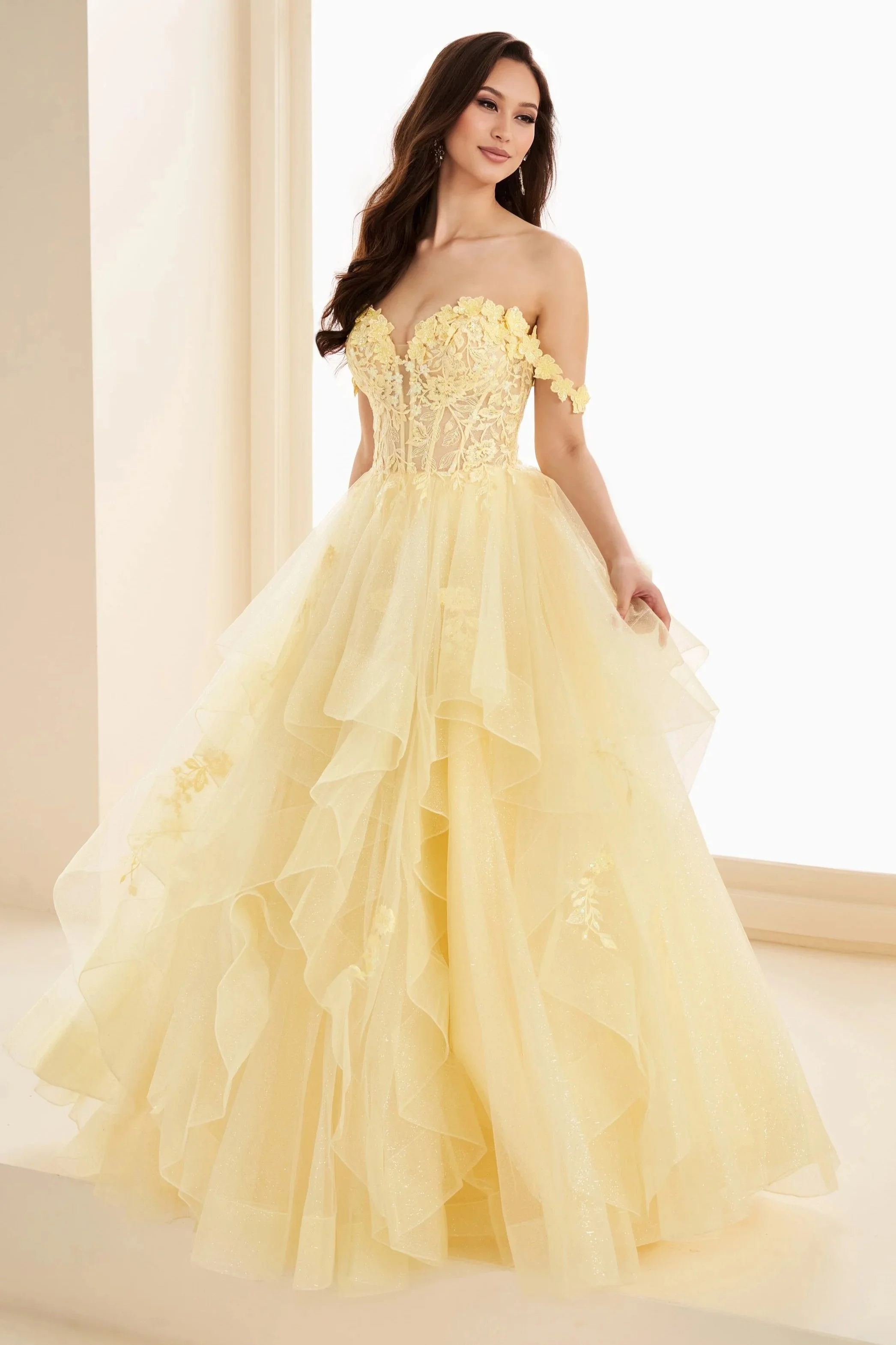 Ellie Wilde EW35084 yellow prom dress featuring floral appliqué bodice, off-the-shoulder details, and layered ruffle ball gown skirt