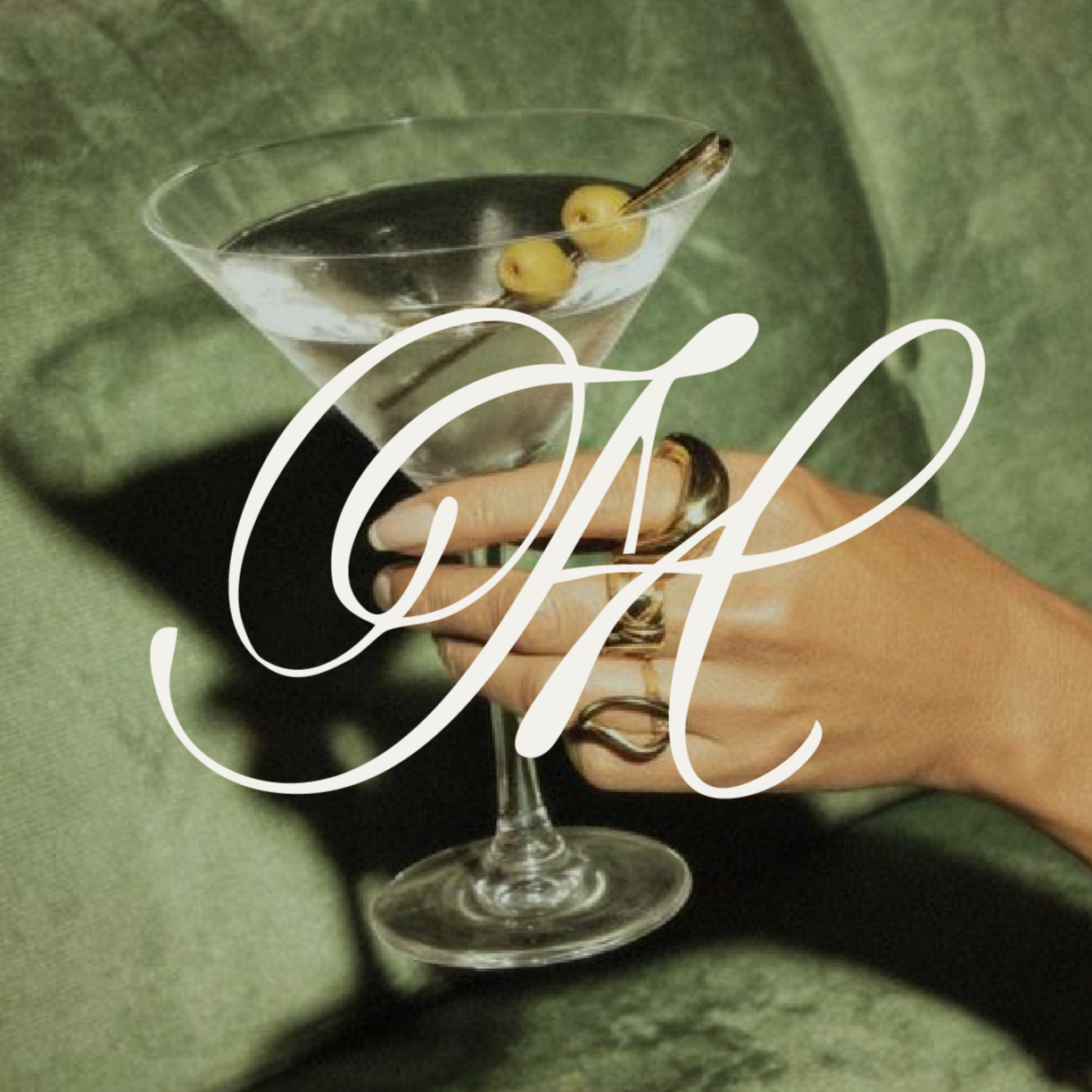 Person holding a martini glass with olives and a skewer, with the word 'CAF' overlaid.