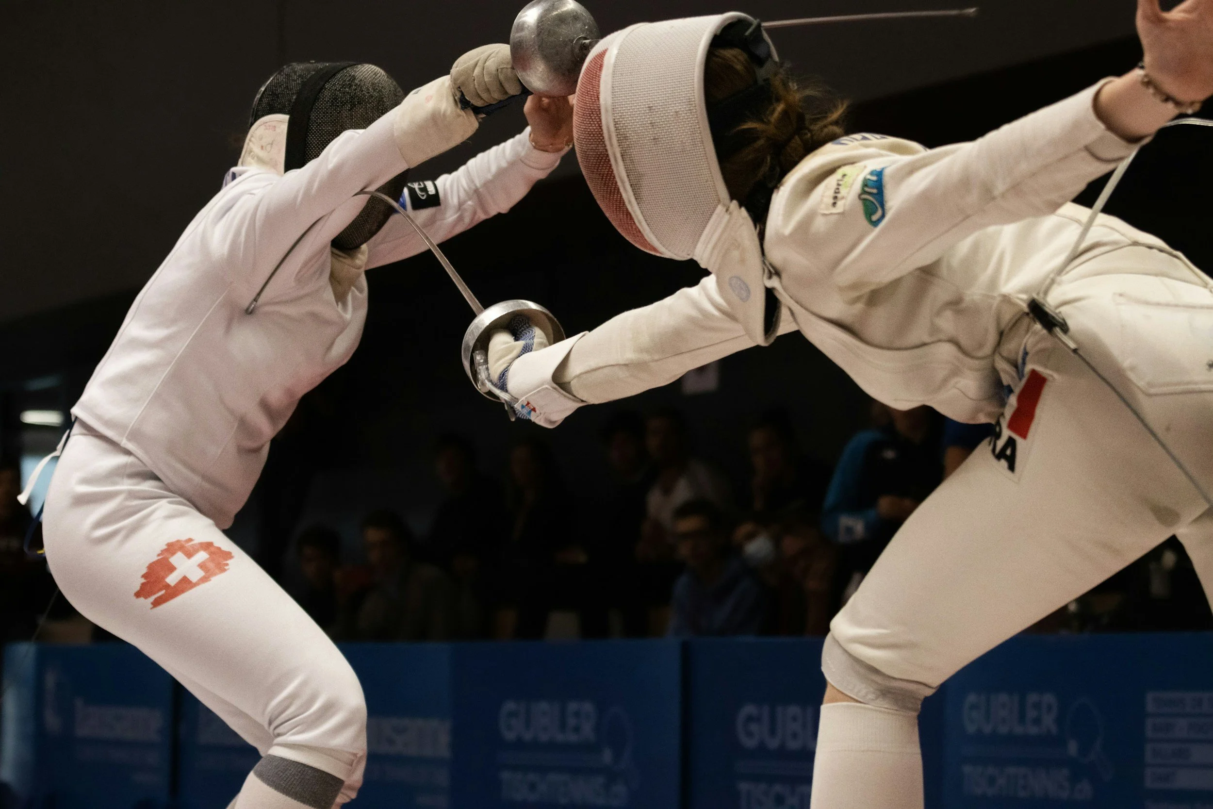 Women are in a studio competitively sparring in Fencing Gear