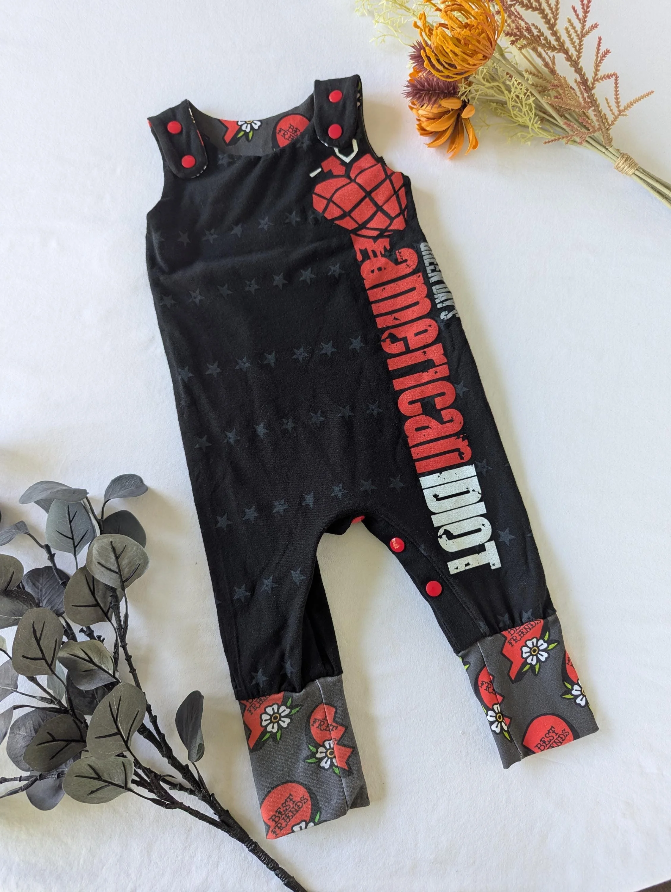 Black baby romper with a graphic print of Green Day American Idiot with heart shaped grenade, cuffs grey with best friend written in red hearts