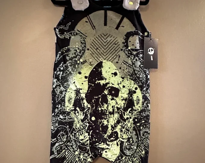 A black and yellow graphic design on a clothing item, featuring a skull with abstract patterns and robotic elements.
