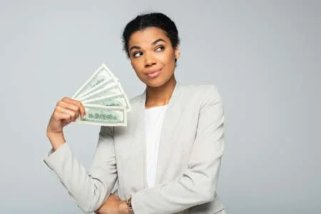 Woman holding dollar bills, wearing a light-colored suit, looking to the side