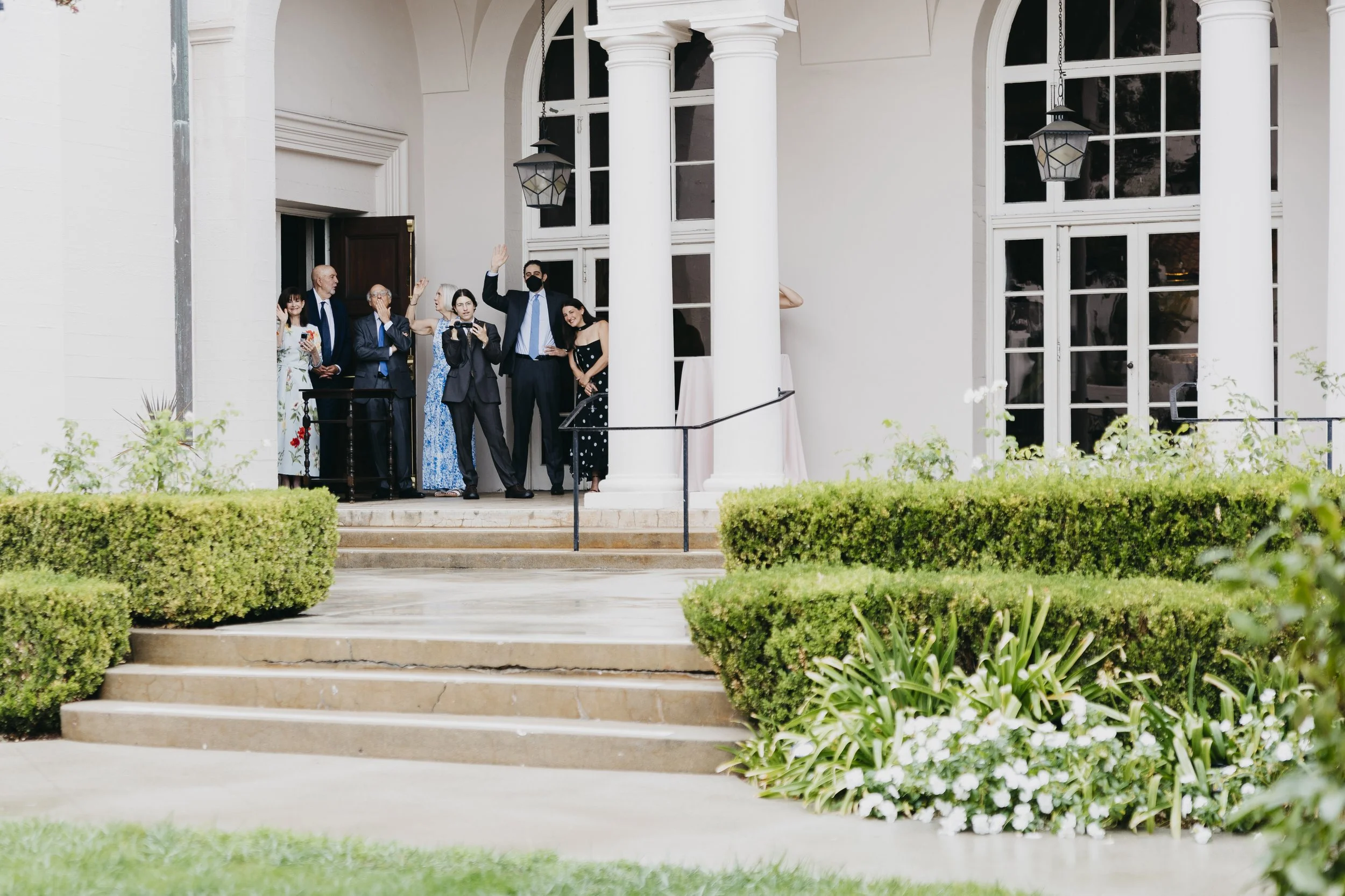 Group of women in colorful dresses holding bouquets of flowers at a wedding or celebration outdoors