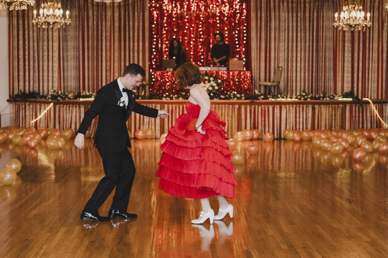 A decorated dining table with vases of colorful flowers, clear glasses, plates, silverware, and a tall candle holder with a pink candle, and a transparent acrylic table number.