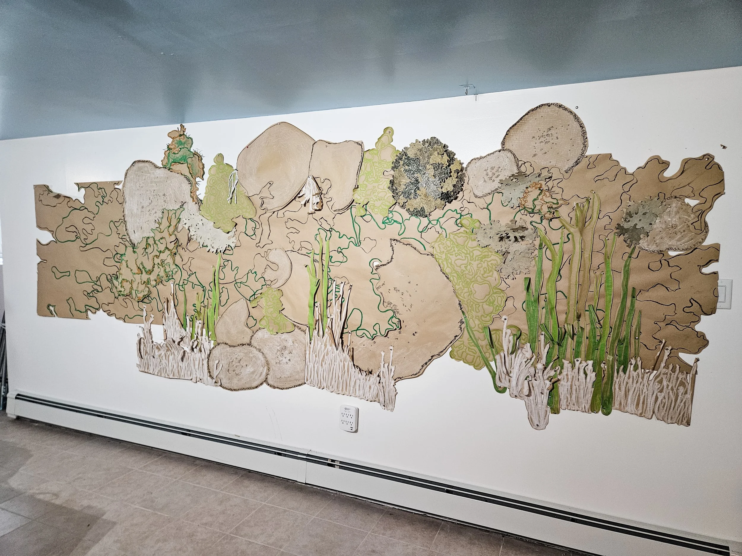 An in-progress cut paper collage mural on the studio wall of Allison Belolan inspired by lichen