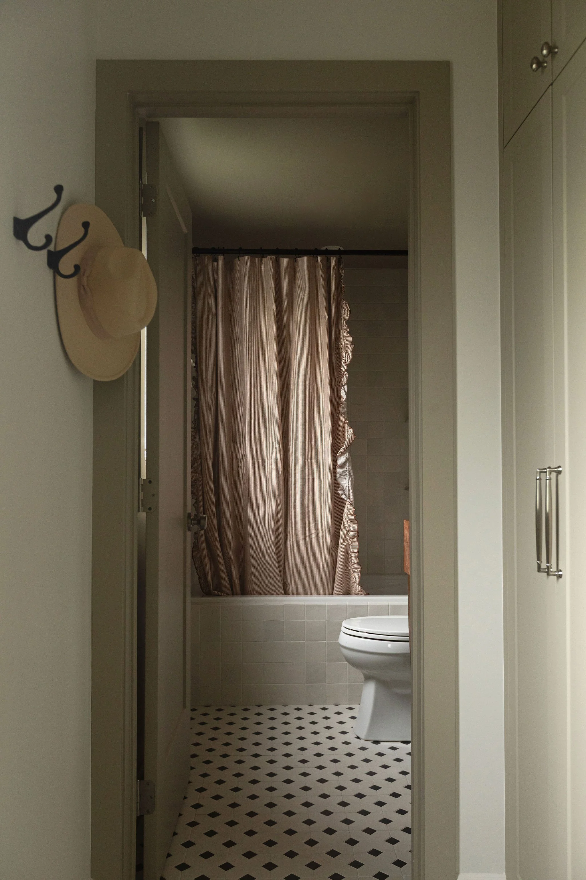 Bathroom renovation with a black and white patterned tile floor, white bathtub and warm neutral finishes.