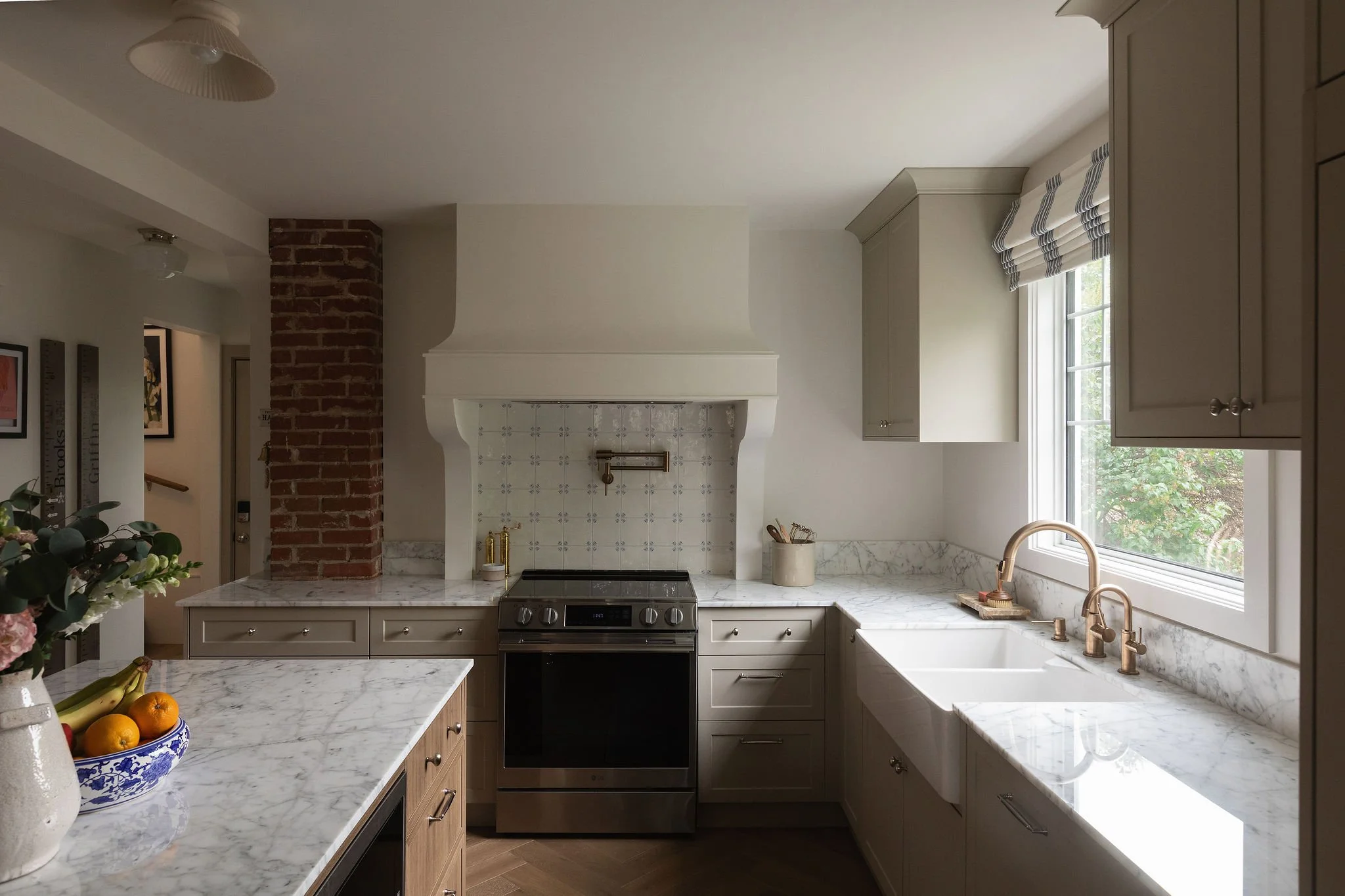 Custom kitchen range hood with Delft-inspired backsplash tile, beige cabinets and marble countertops in an Edmonton cottage renovation.