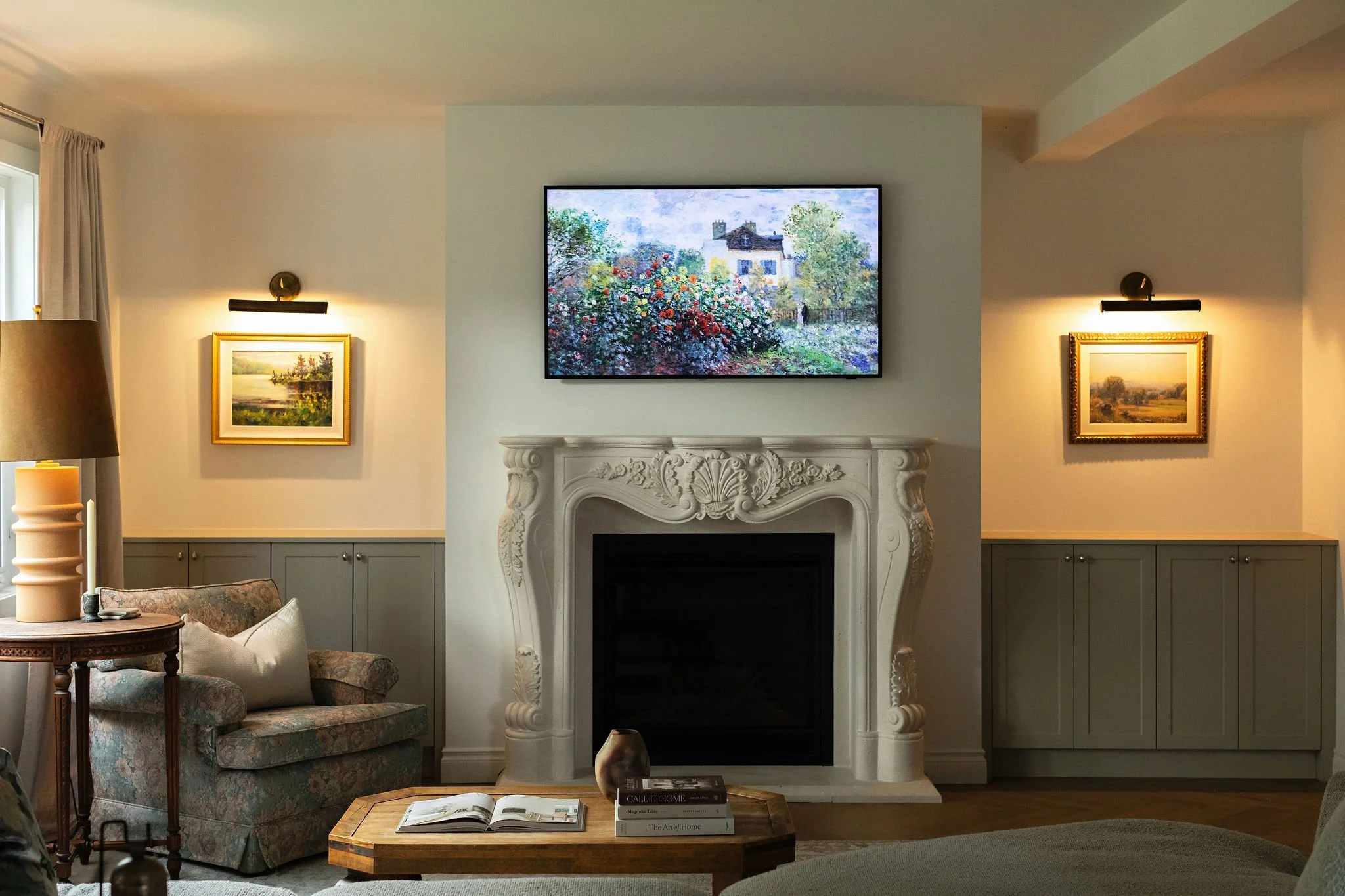 Living room in The Bell cottage renovation featuring a decorative fireplace surround, taupe built-ins and collected artwork.