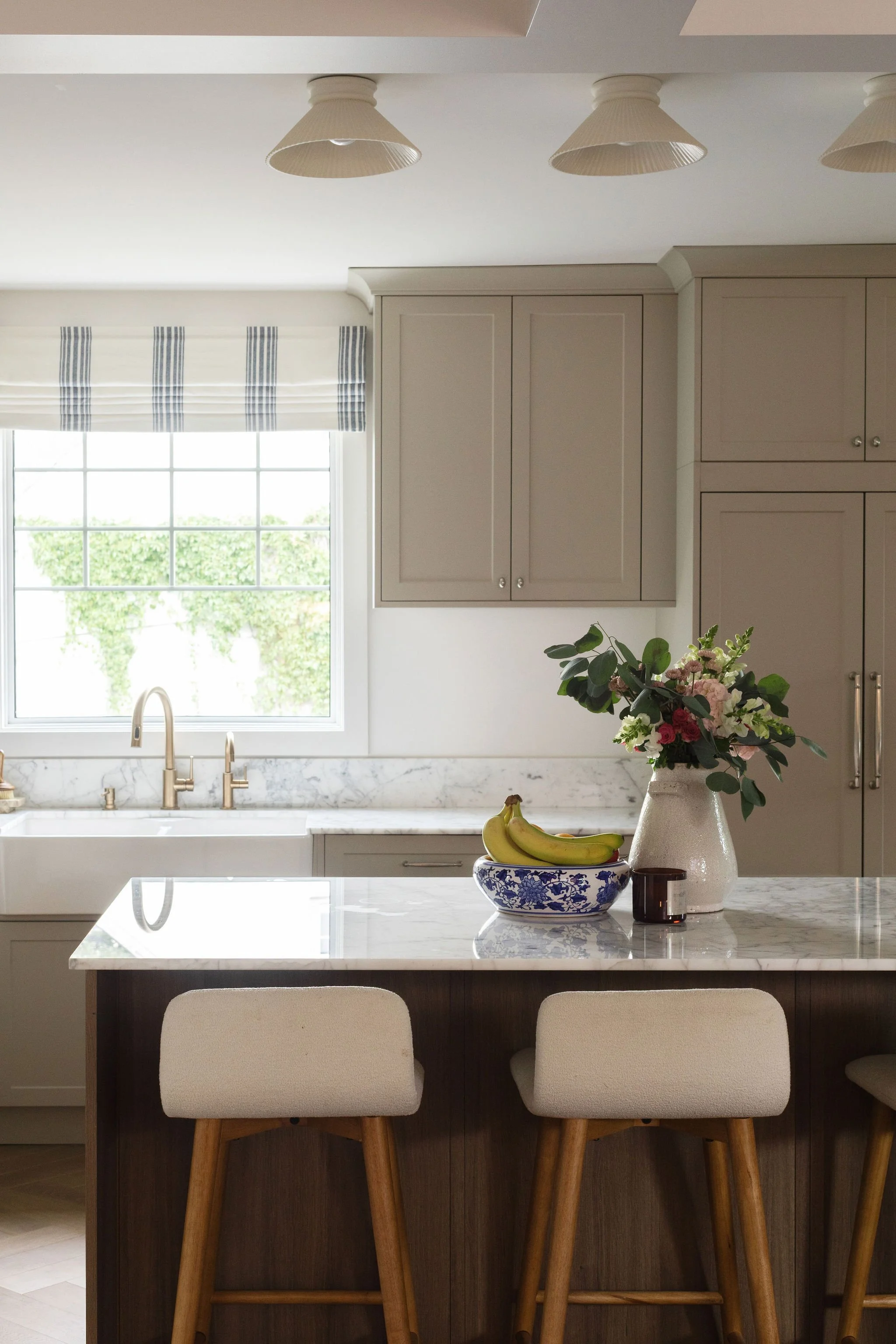 Edmonton kitchen renovation with a dark wood island, beige cabinetry and natural Gioia marble countertops.