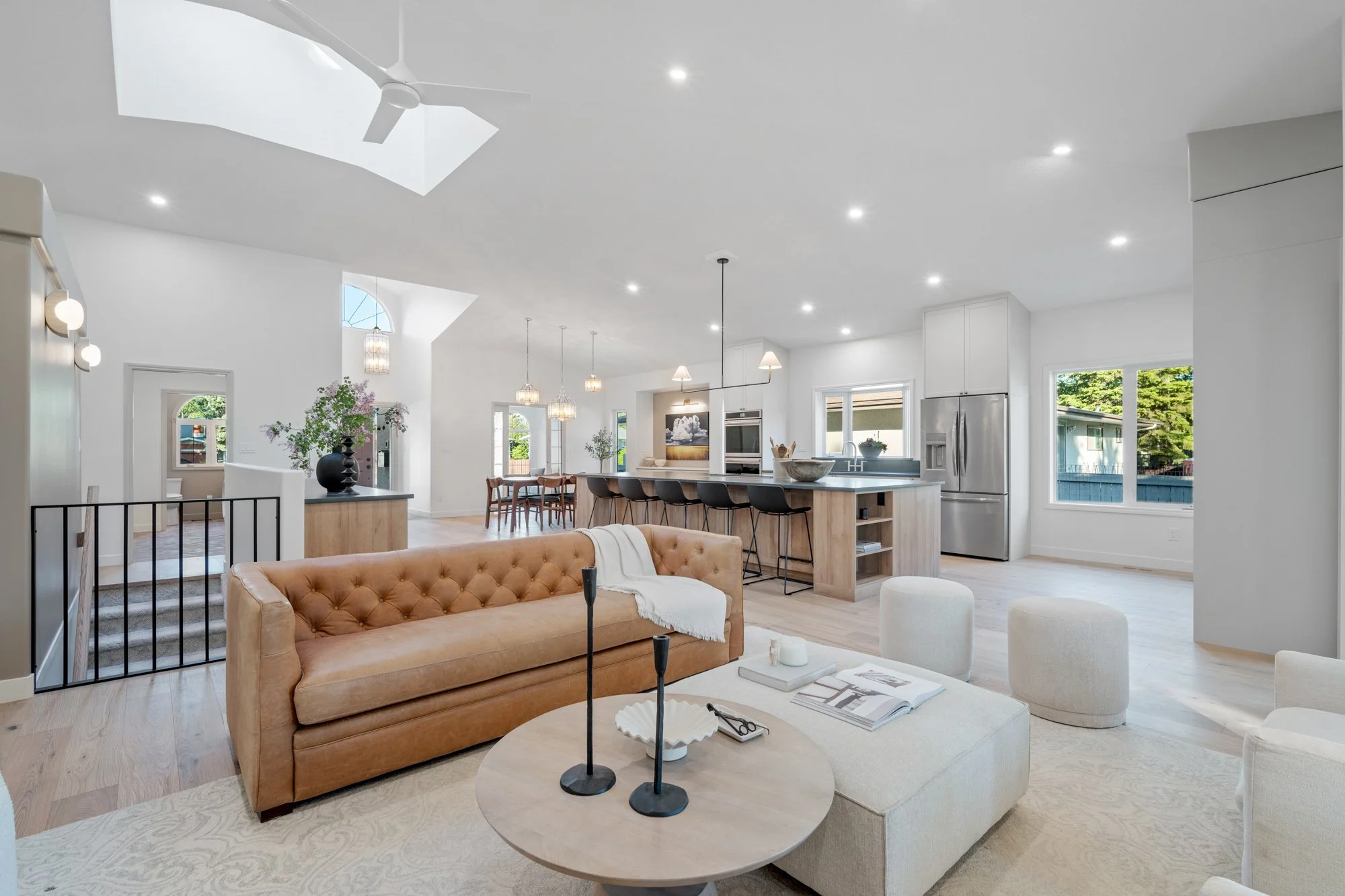 Open living area and kitchen with high ceilings and skylights. Wood and white kitchen, white oak flooring