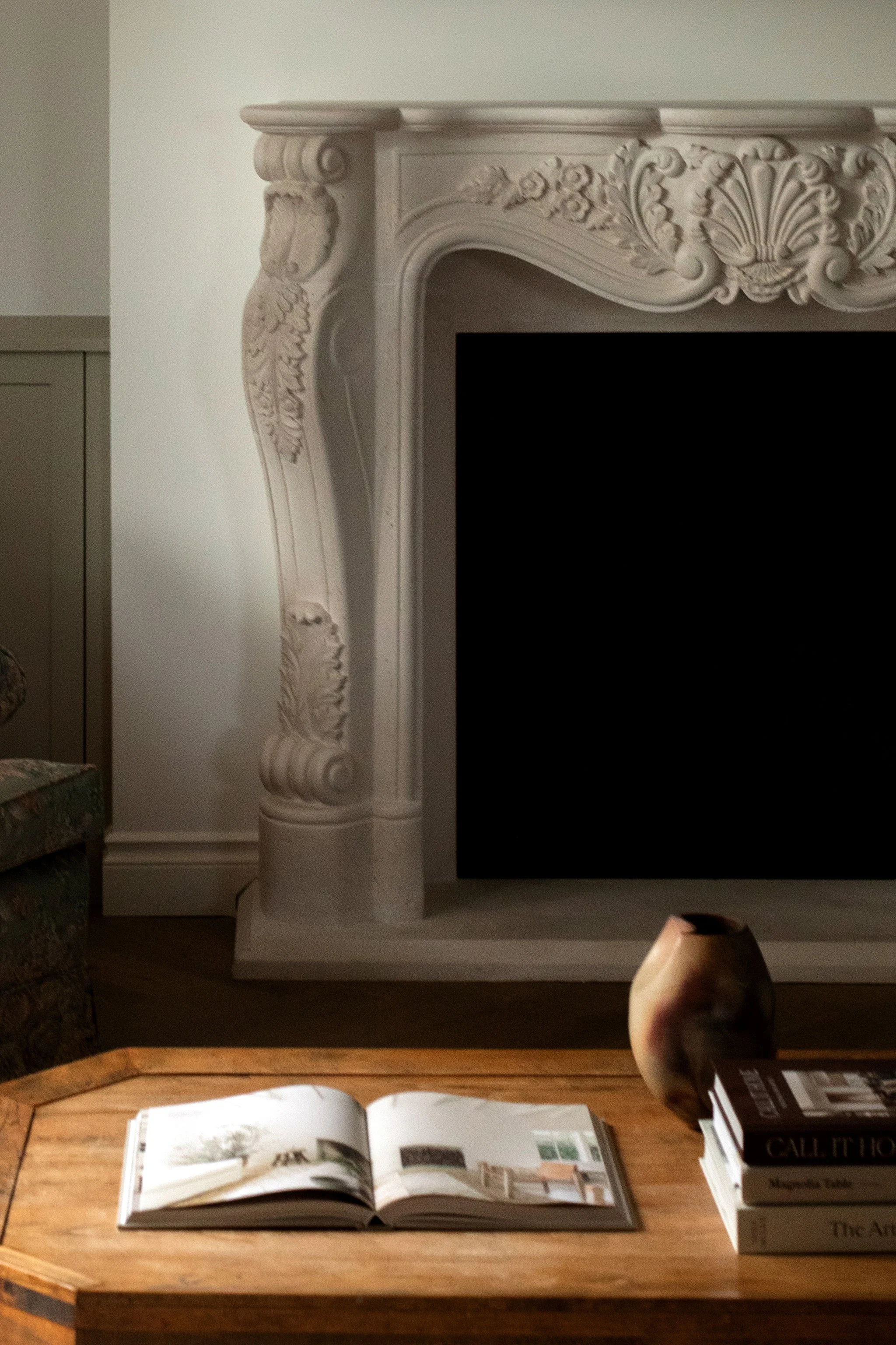 Close-up of the ornate fireplace surround and natural wood coffee table in The Bell cottage renovation.