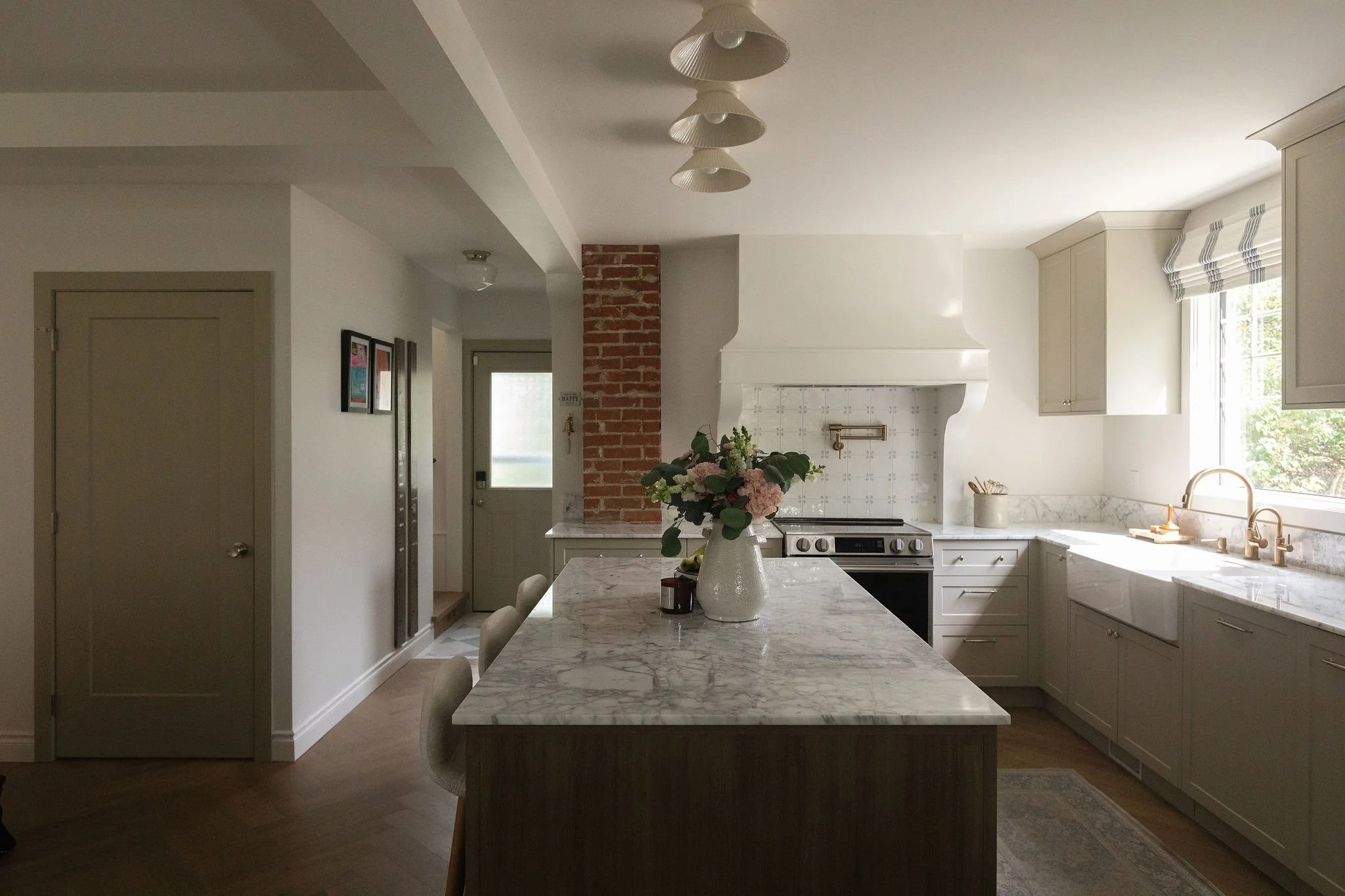 Edmonton cottage kitchen featuring a generous marble island, custom cabinetry and a statement drywall range hood.