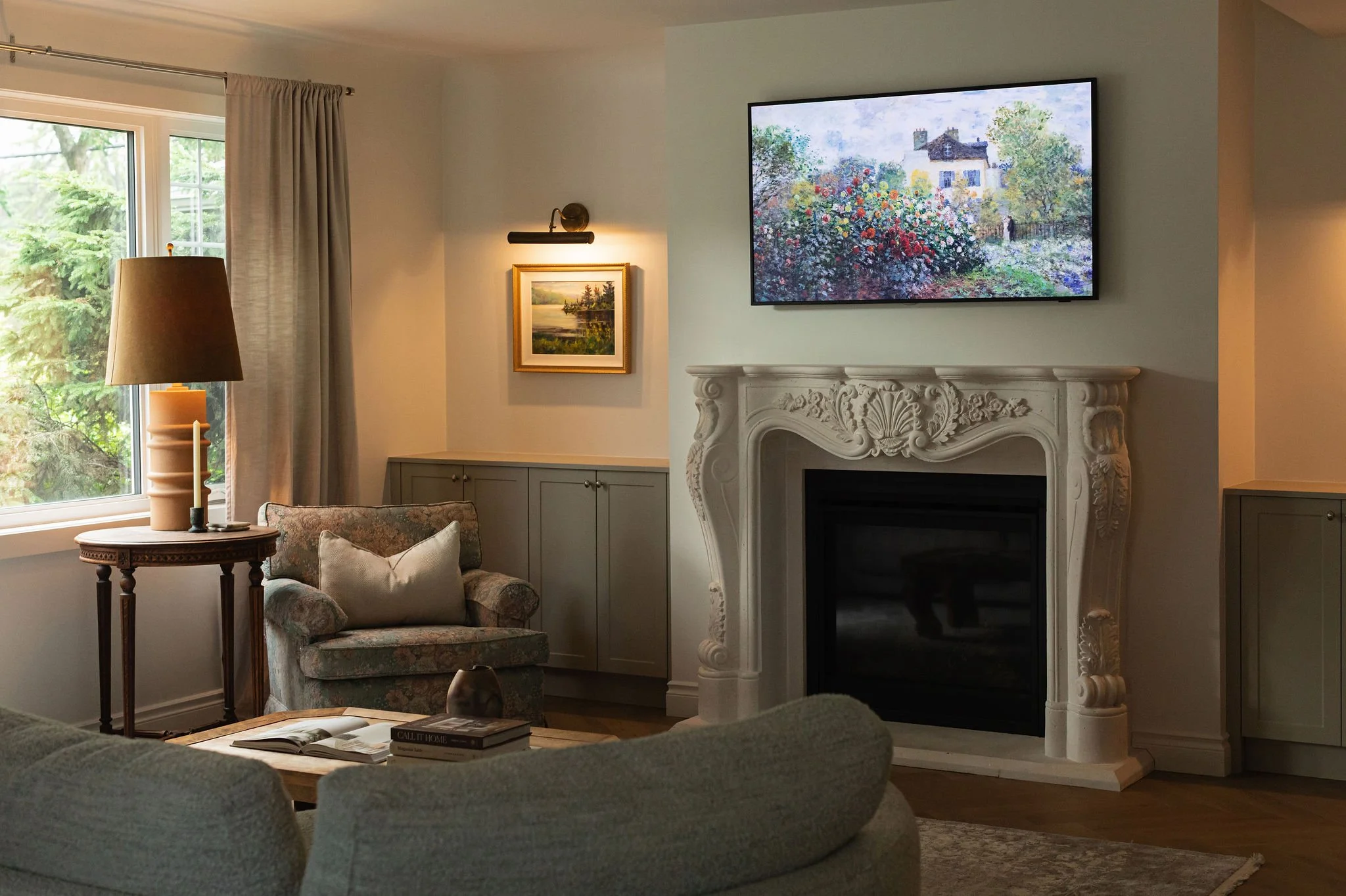 Living room in The Bell cottage renovation featuring a decorative fireplace surround, taupe built-ins and collected artwork