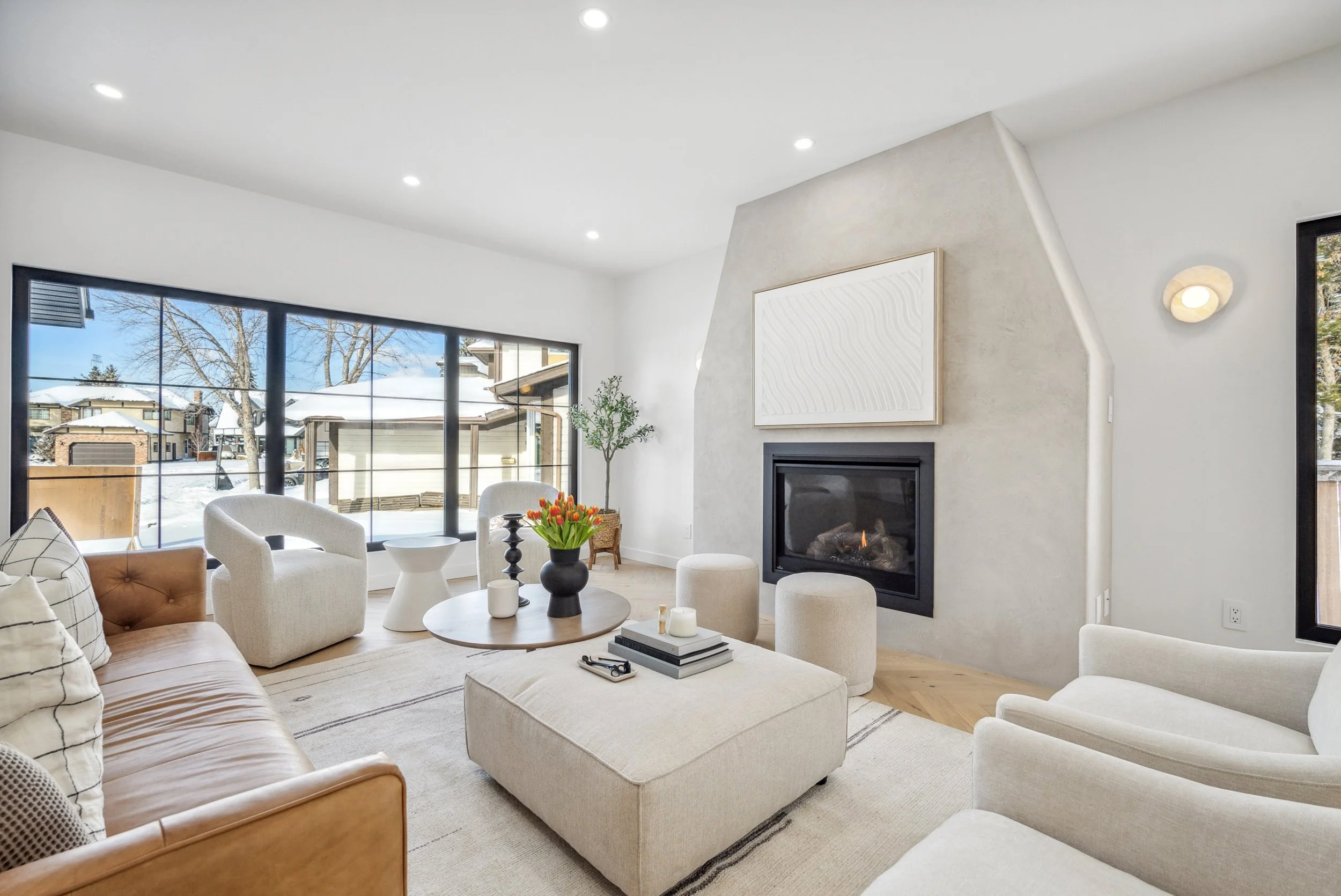 living room with big windows and limewash gas fireplace., neutral furniture and herringbone wood floors