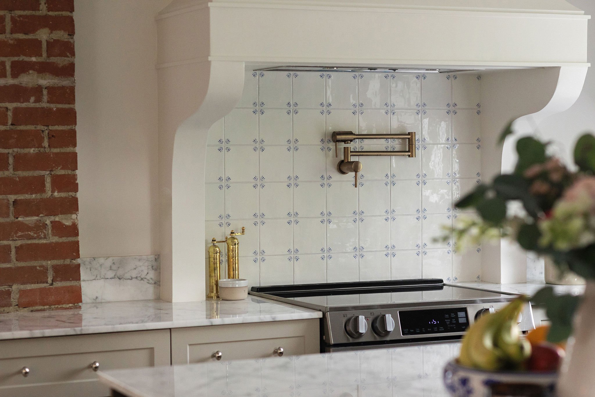 Custom kitchen renovation in Edmonton with a drywall range hood, warm neutral cabinetry, and timeless natural stone finishes.