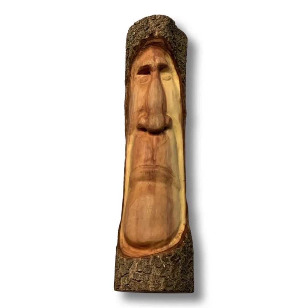 A wooden sculpture of a face with detailed features carved into a small log.
