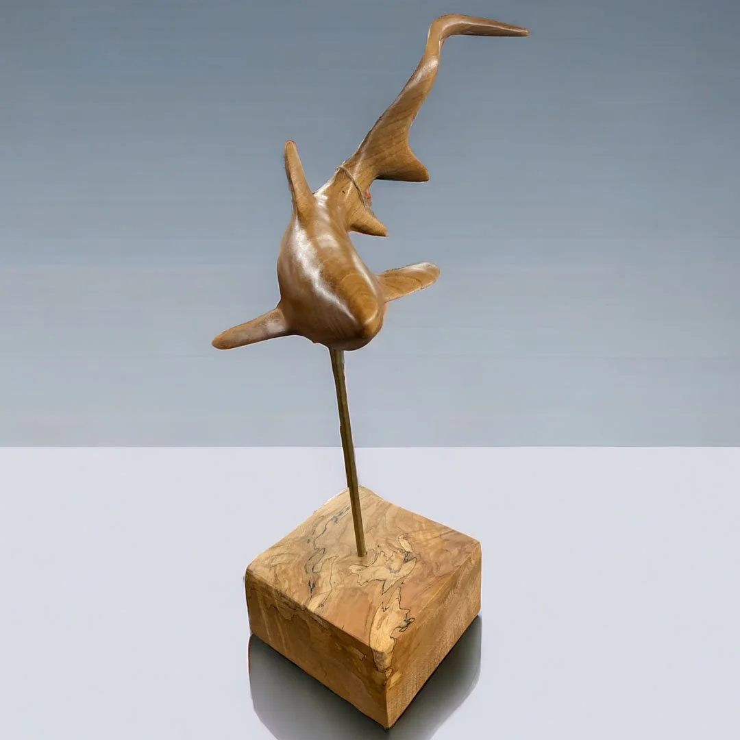 Wooden sculpture of a thresher shark mounted on a wooden base.