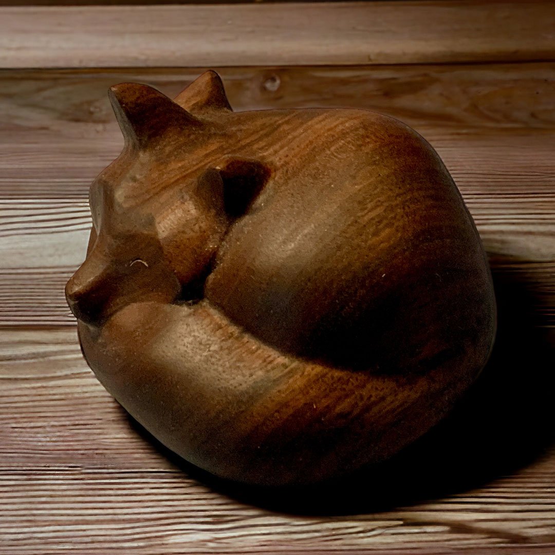 Wooden sculpture of a sleeping fox on a wooden surface.
