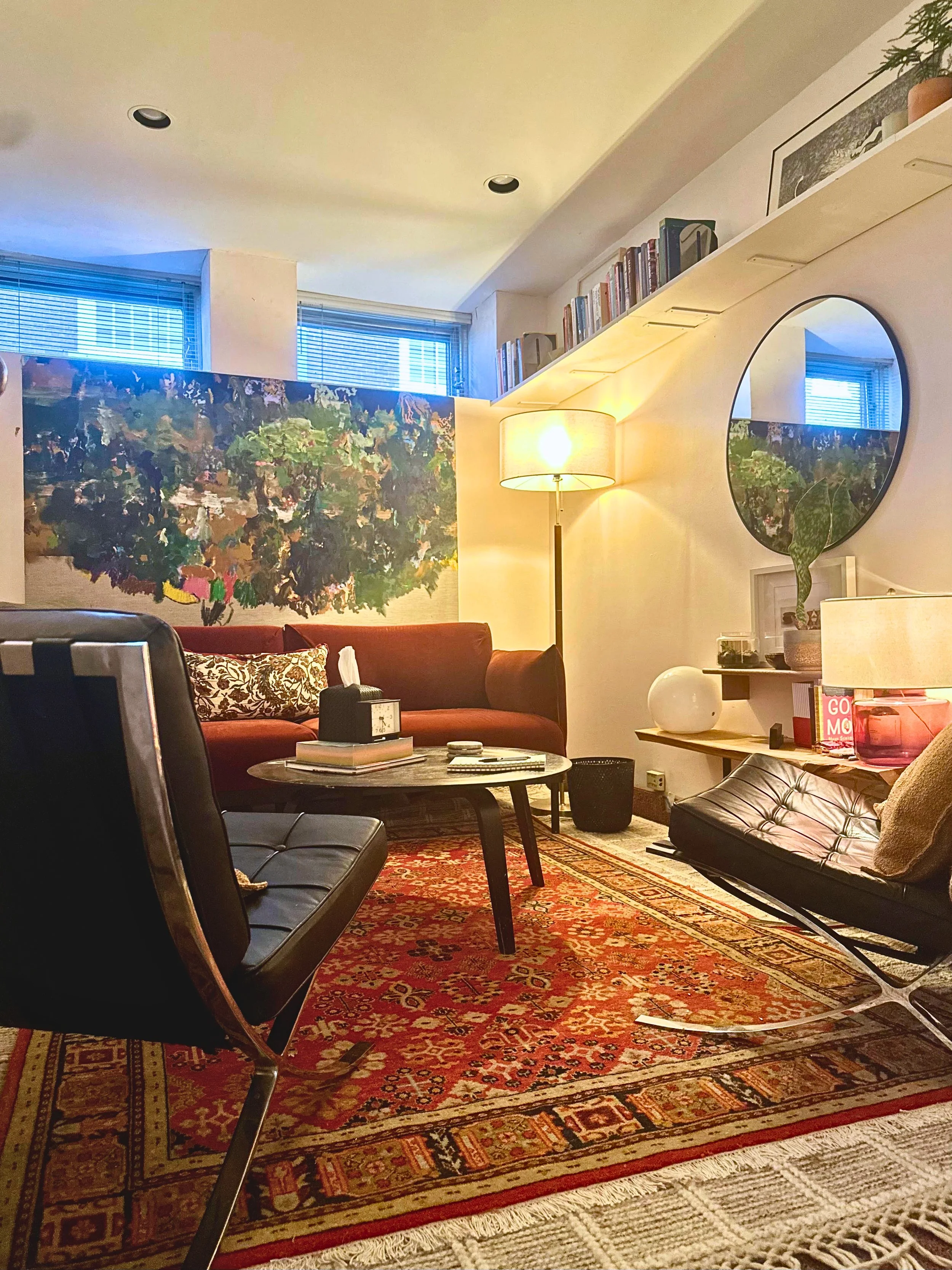 Therapy office featuring red patterned rug, black round table and chairs and a red sofa, with overall mid-century modern look