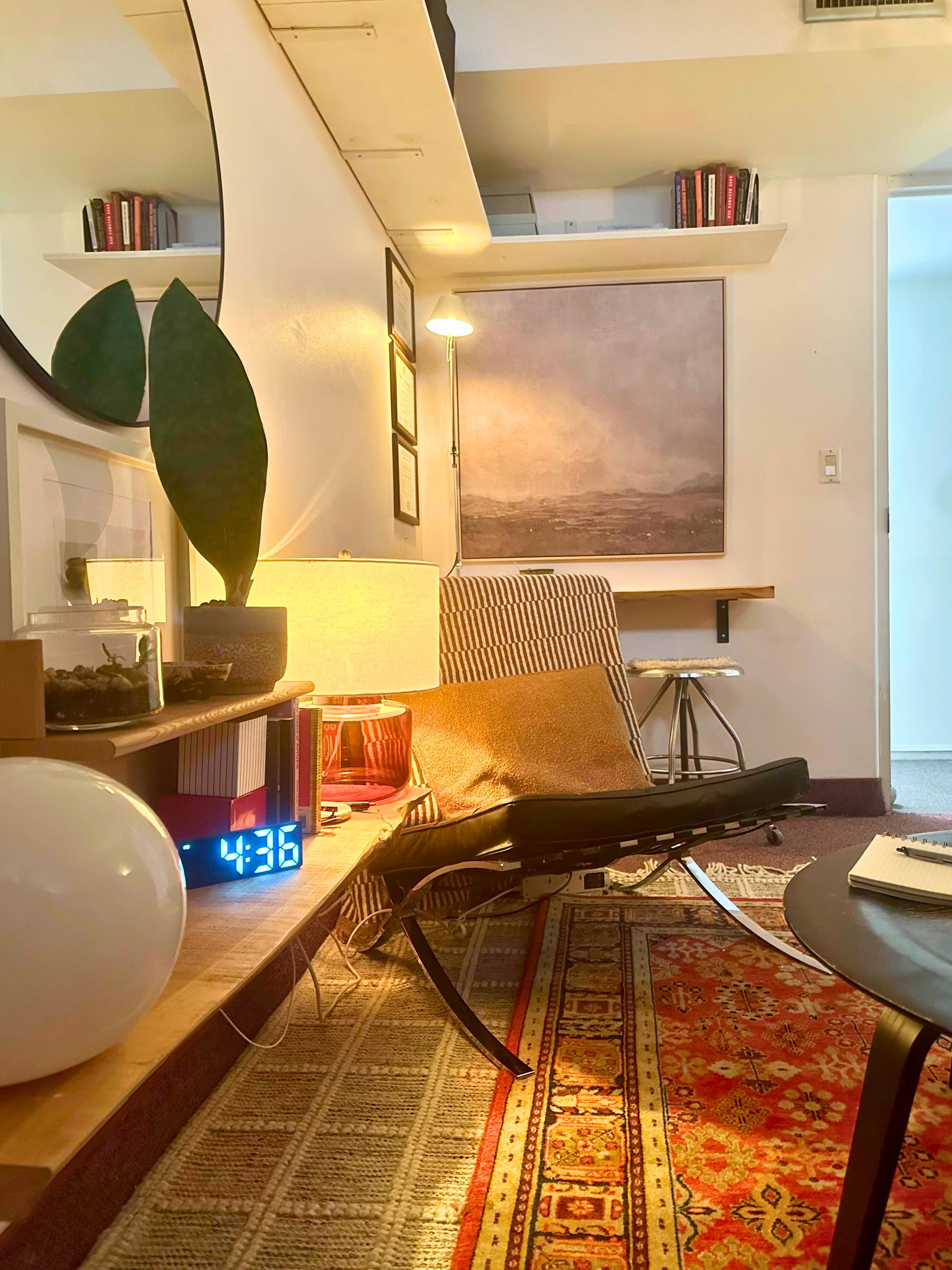 Therapy office featuring red patterned rug, black round table and chair, with overall mid-century modern look