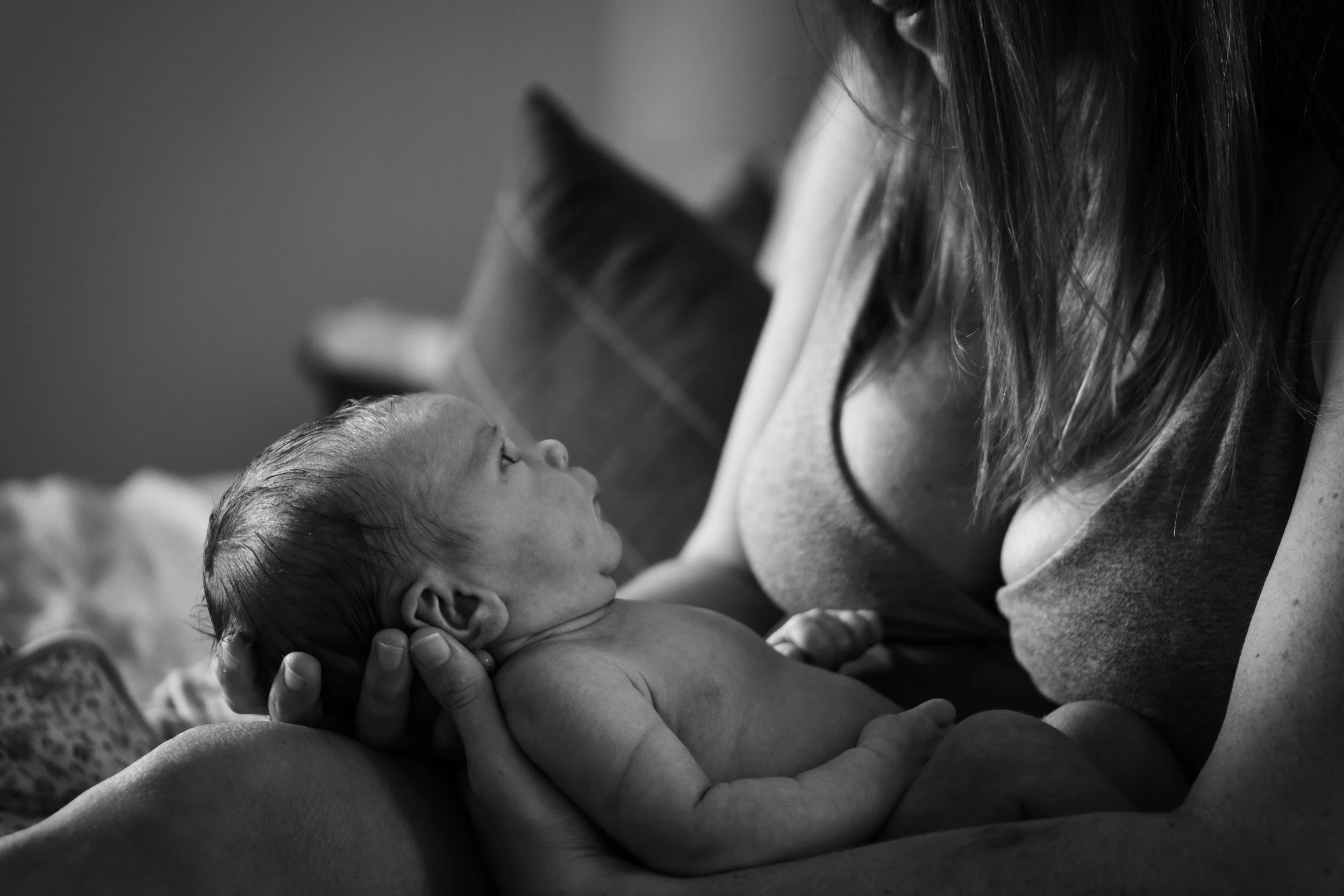 A woman holding a newborn baby in her arms, looking at the baby lovingly.