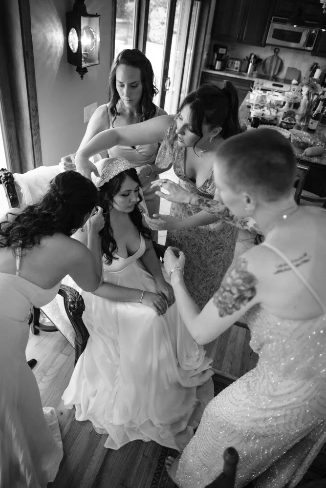 A bride in a wedding dress getting ready with her bridesmaids and friends in a kitchen.