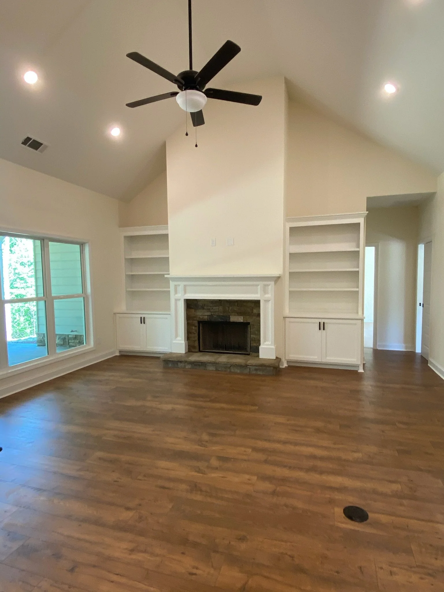 Vaulted living room with custom built-ins creates a wow factor. Added details, like the floor outlets, are thoughtful touches that add functionality to the home.