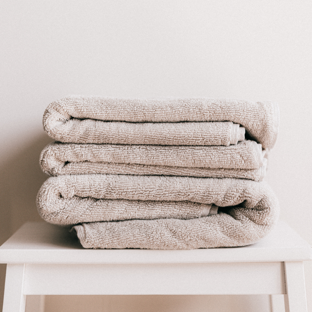 A set of beige Airbnb or spa towels neatly folded on a white table.