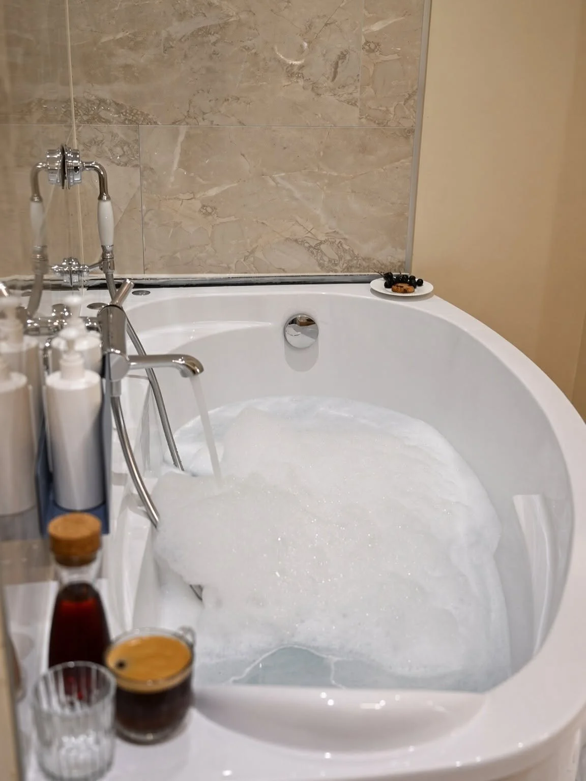 Baignoire balnéo d'angle dans une salle de bain aux murs effet marbre