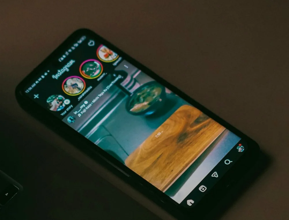 Smartphone posé sur un bureau, affichant un fil de réseau social