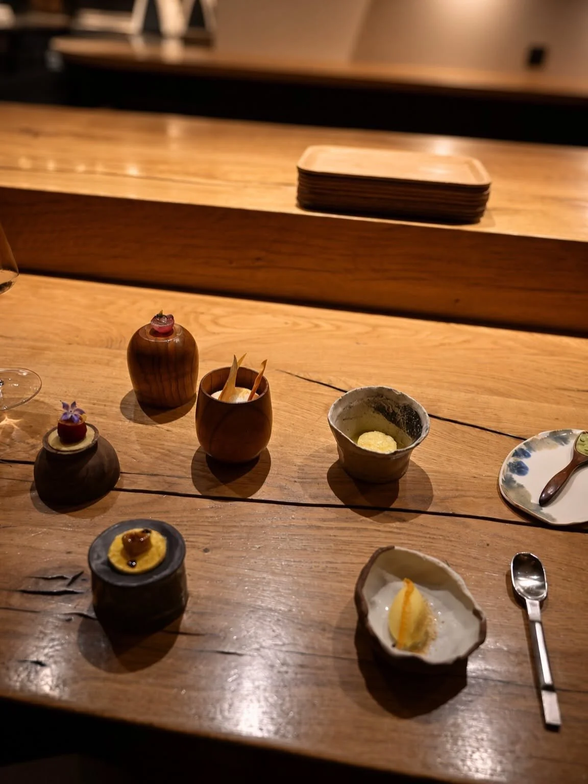 Ronde de petites bouchées servies dans des contenants en céramique et en bois alignés sur le comptoir