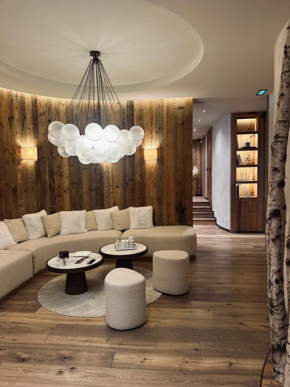 Salon lounge sous un lustre en boules de verre, canap&eacute; cr&egrave;me et bois