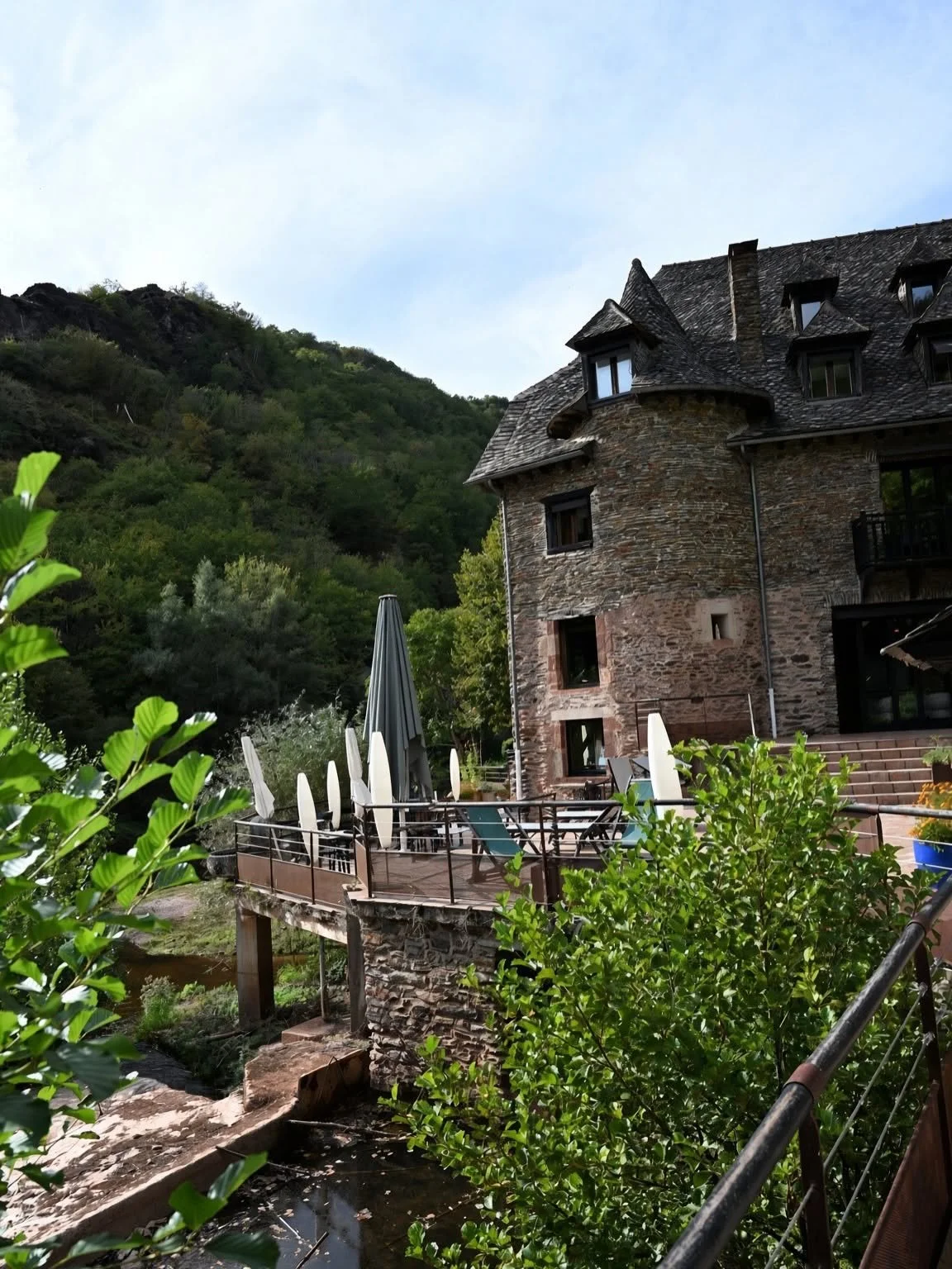 Vue sur le moulin, les terrasses et la végétation au bord de la rivière
