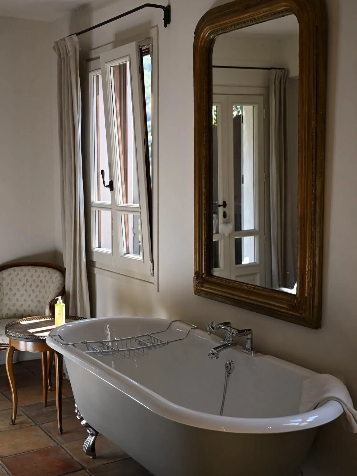 Baignoire à pieds devant un miroir ancien dans une chambre lumineuse