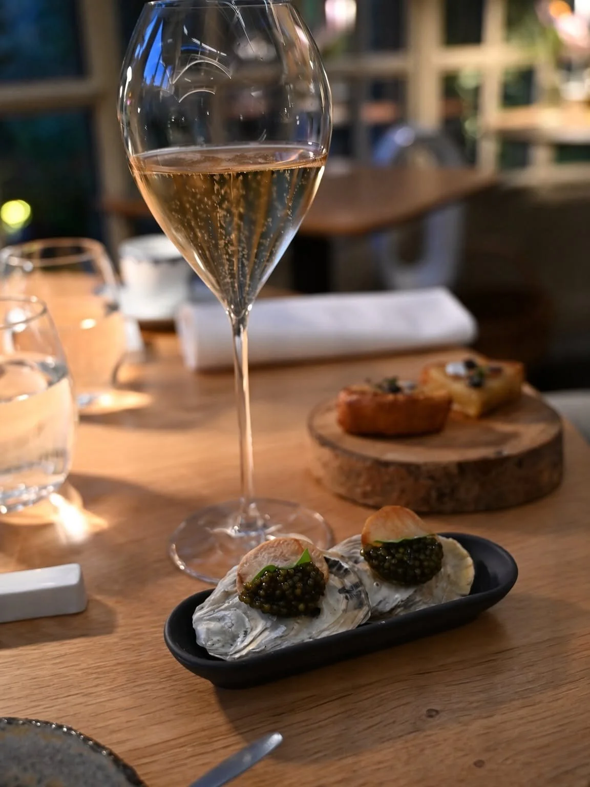 Coupe de champagne et bouchées sur une table en bois au Clair de la Plume