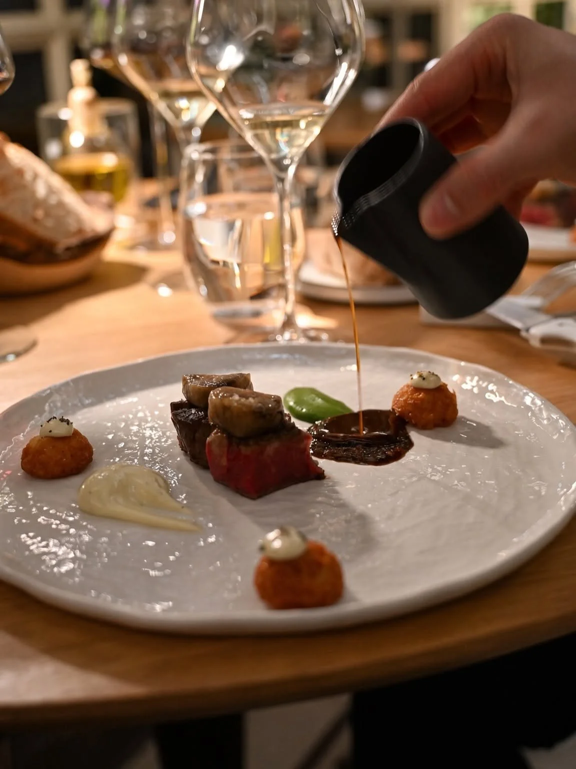 Sauce versée à table sur une assiette de viande et légumes