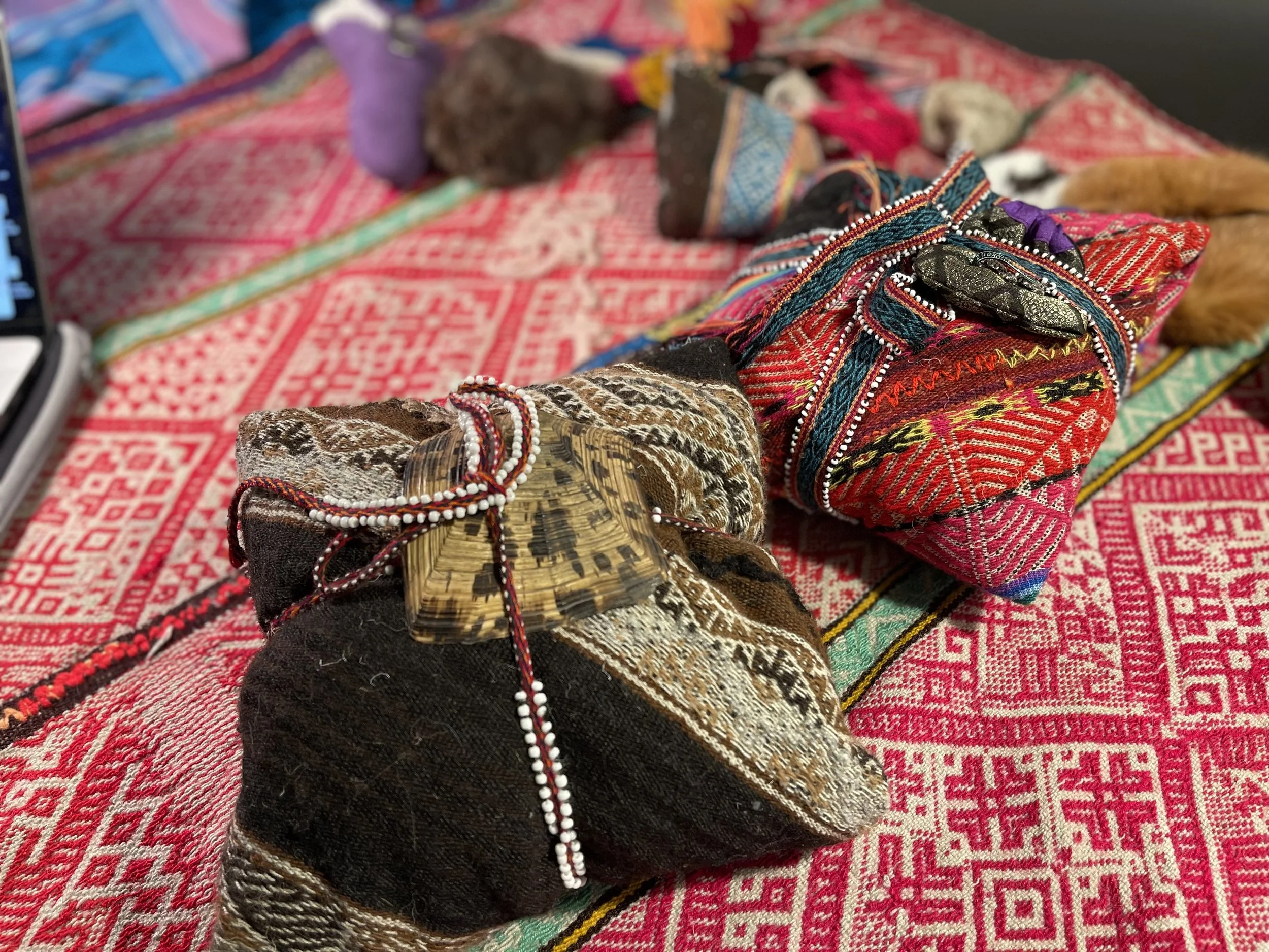 Traditionelle Stoffbündel auf einem gemusterten Tisch. Die Bündel sind mit bunten Mustern verziert und mit Kordeln zusammengebunden.