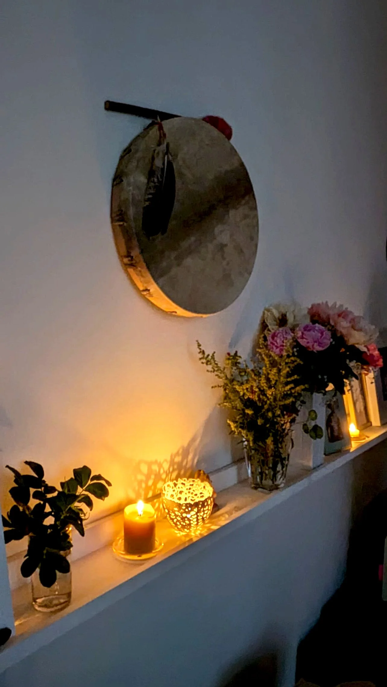 Schamanische Trommel über einem mit Kerzen, Pflanzen und Blumen gestalteten Praxisraum