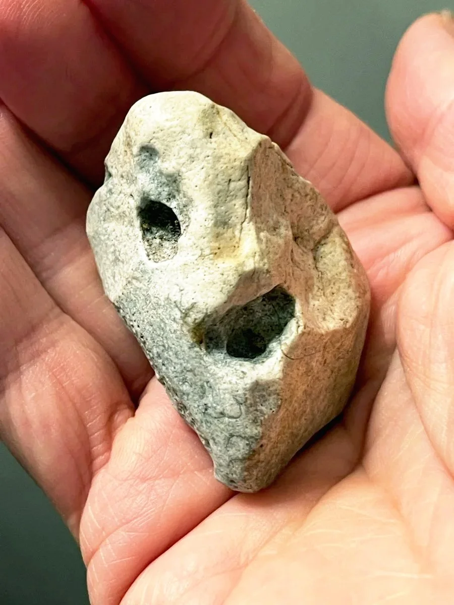 Naturstein mit mehreren Vertiefungen liegt in einer geöffneten Hand