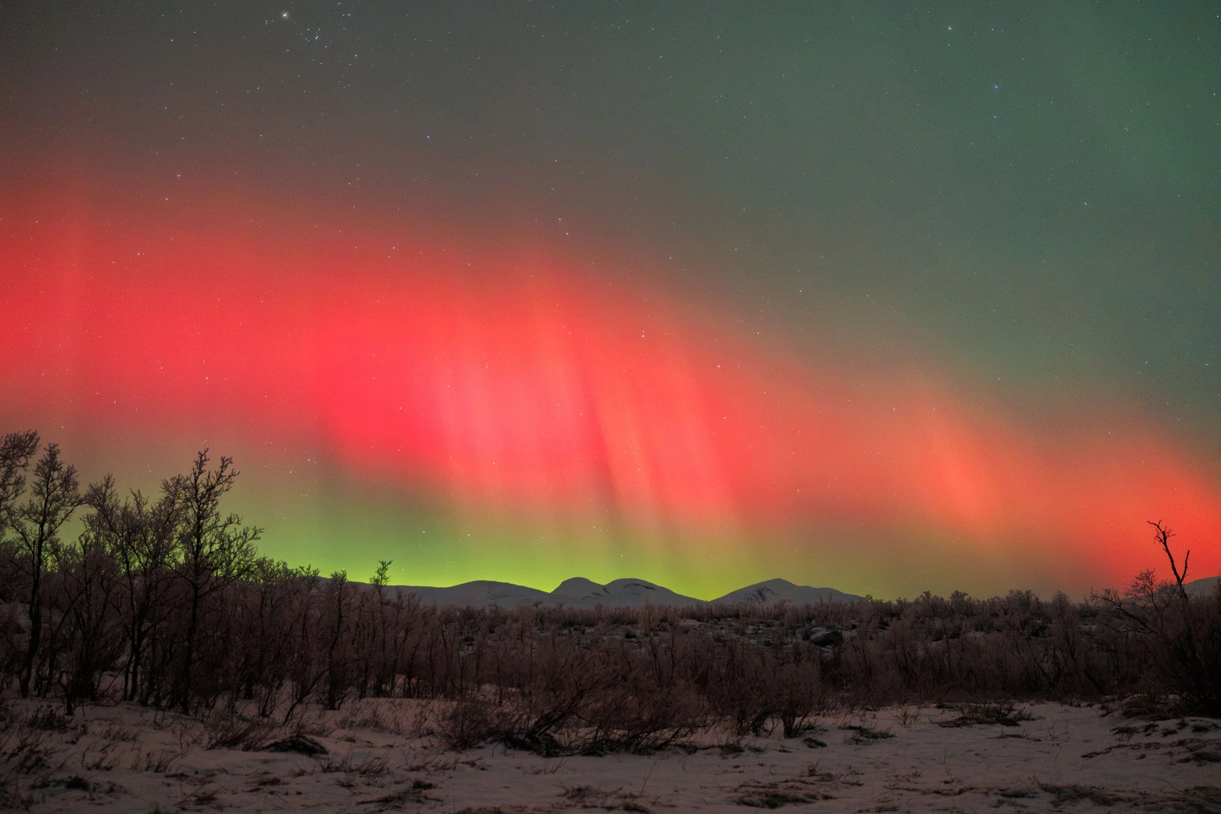 A bright red and strong aurora over the Abisko alps during a solar storm