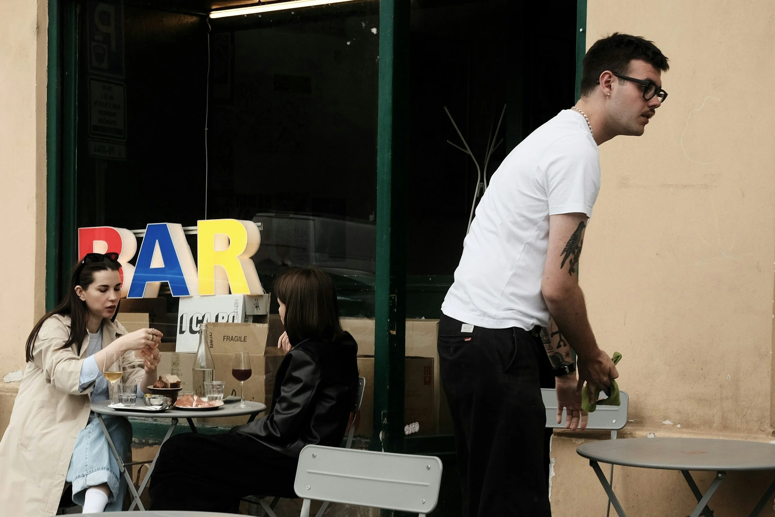 A small-business owner serving customers at an outdoor cafe bar