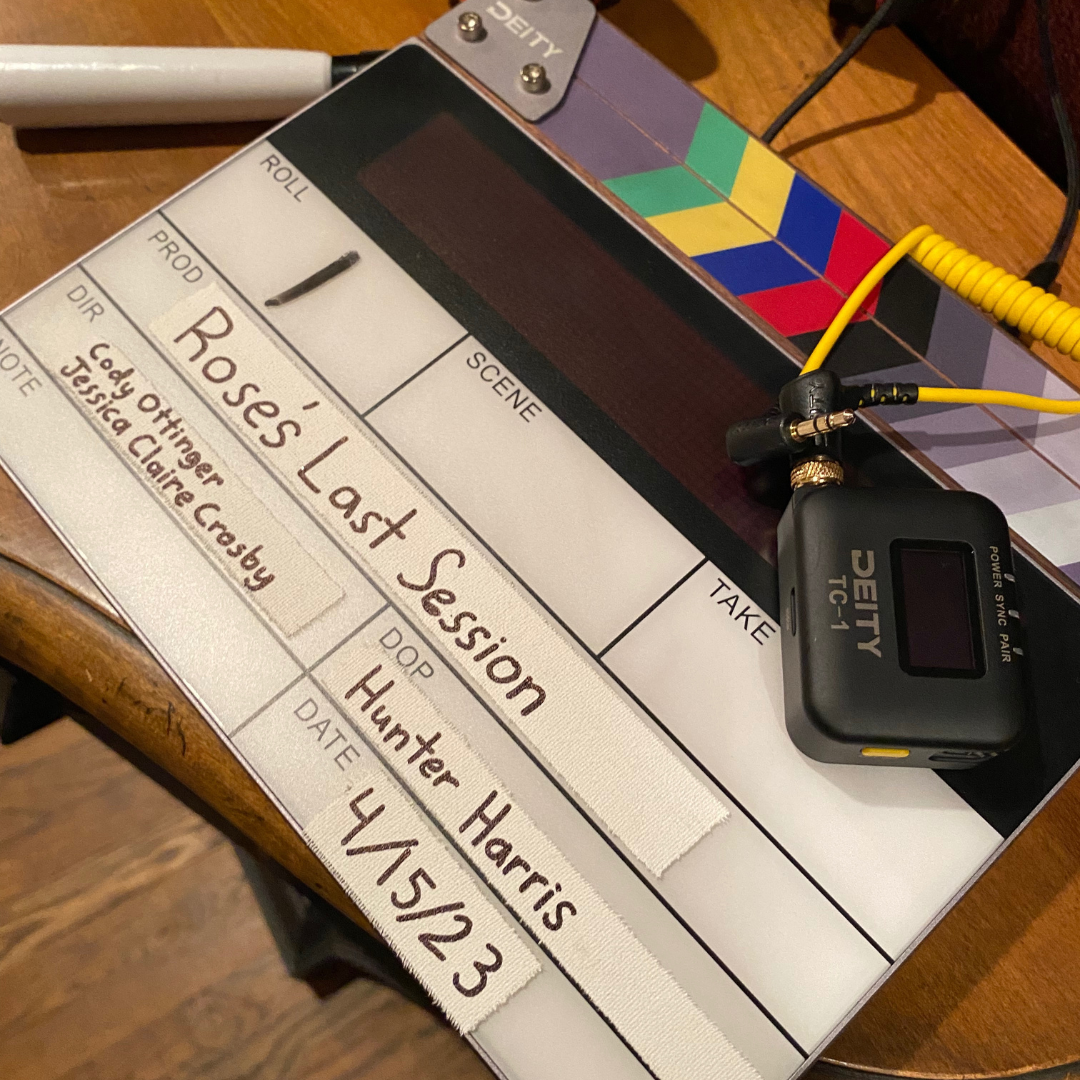Clapperboard for a film titled "Rose's Last Session," with a Deity TCG-1 wireless microphone attached on a wooden surface.