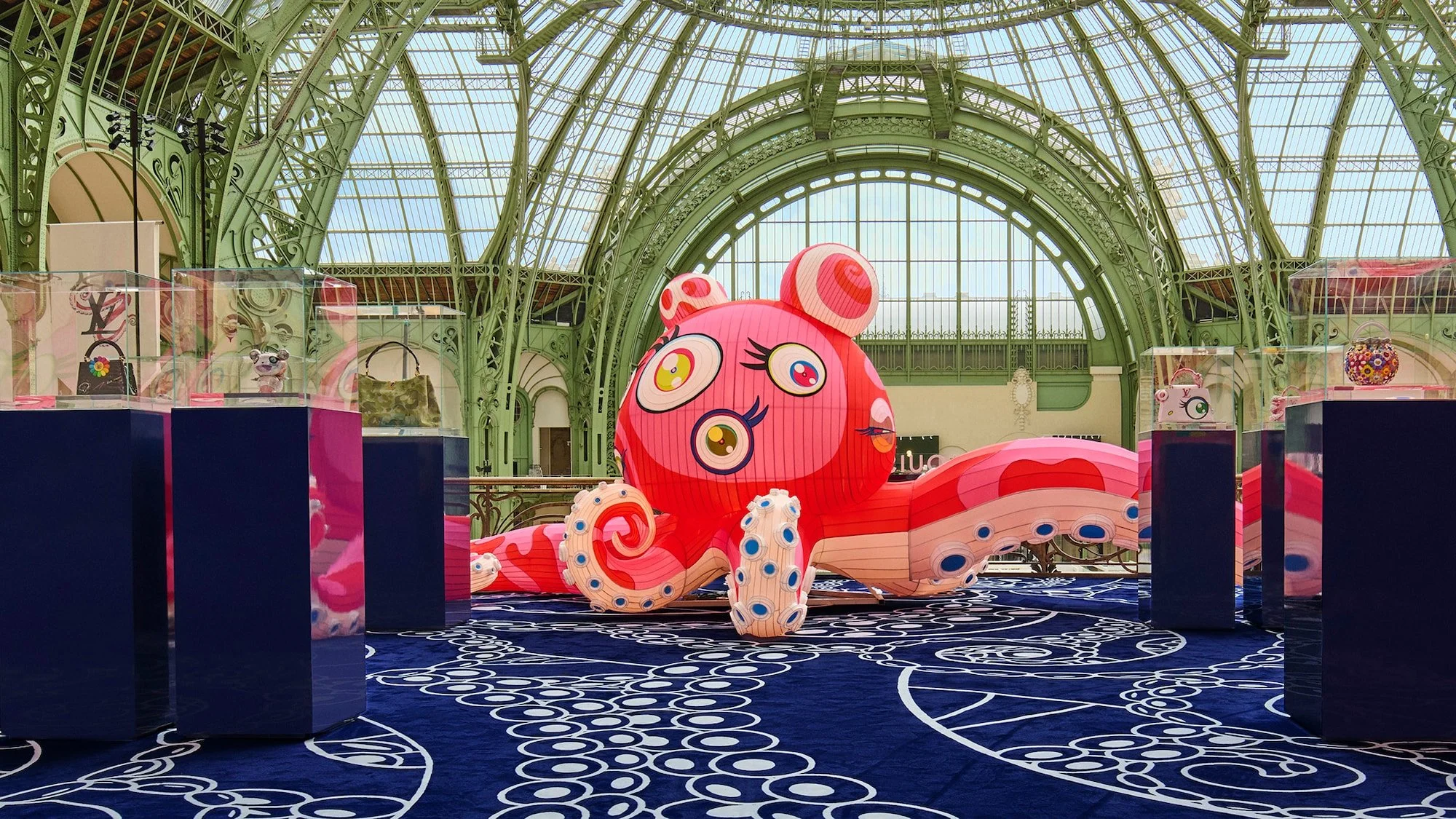 A towering pink octopus sculpture with cartoonish eyes and sprawling tentacles dominates Louis Vuitton’s Art Basel Paris installation, surrounded by display plinths holding the new Murakami-designed Capucines bags.